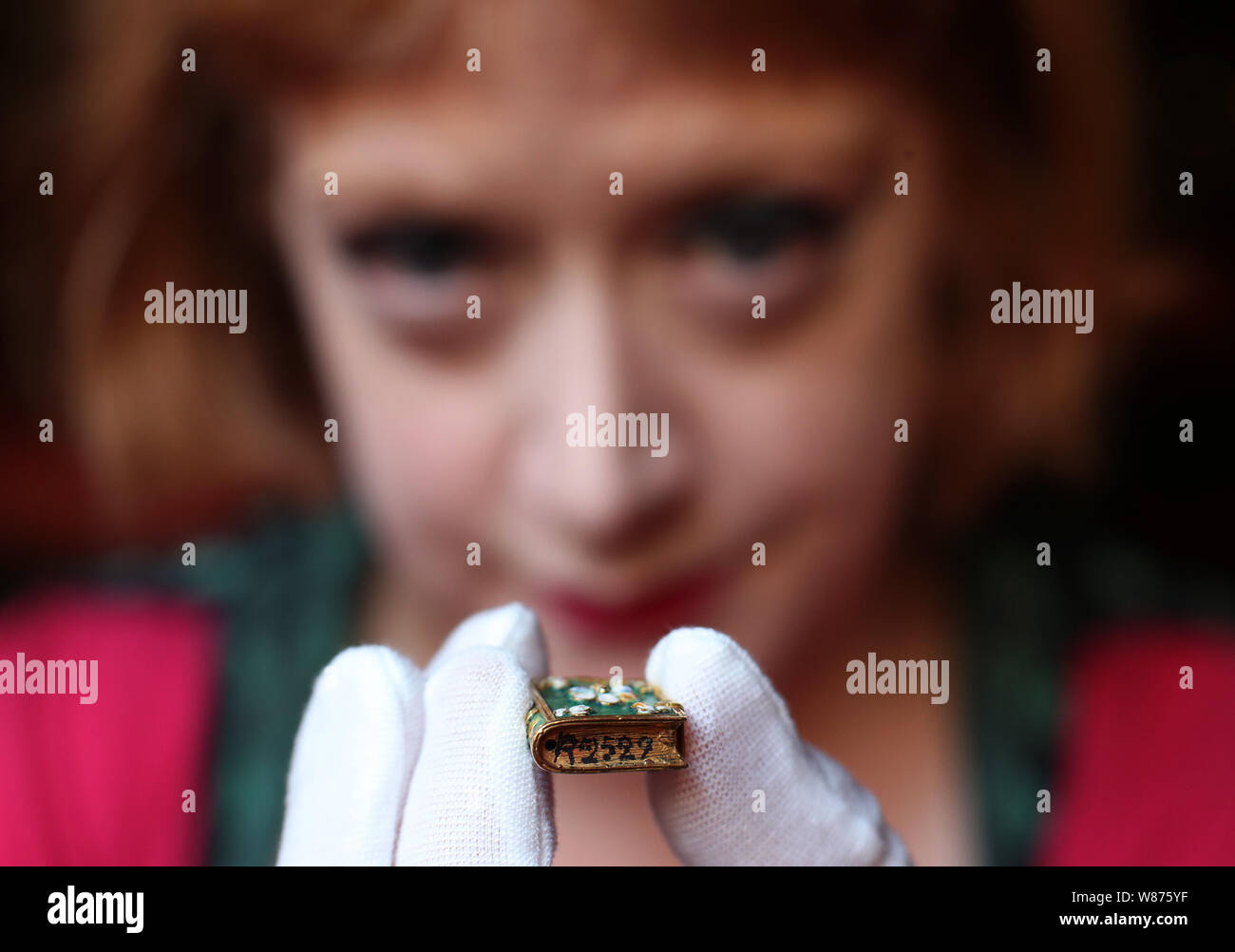 Dr Mia Jackson, Kurator für Dekorative Kunst, Gold und Emaille Anhänger (c.1640-1660) in der Form des Buches, die mit einem Nazi Inventarnummer auf dem Buch Kante, angewendet werden, wenn diese von der Französischen Rothschilds während des Zweiten Weltkriegs beschlagnahmt wurden, Waddesdon Manor, Buckinghamshire, vor der Eröffnung einer Rothschild Treasury Ausstellung, die in eine neue, dauerhafte, Galerie mit mehr als 300 selten gesehene Objekte über zwei Jahrtausende - von einem 1.-Jahrhundert Kamee des Augustus Caesar's Enkel, über Schmuck, Geschenke von Königin Victoria in Objekte, NS-Lager statt. Stockfoto