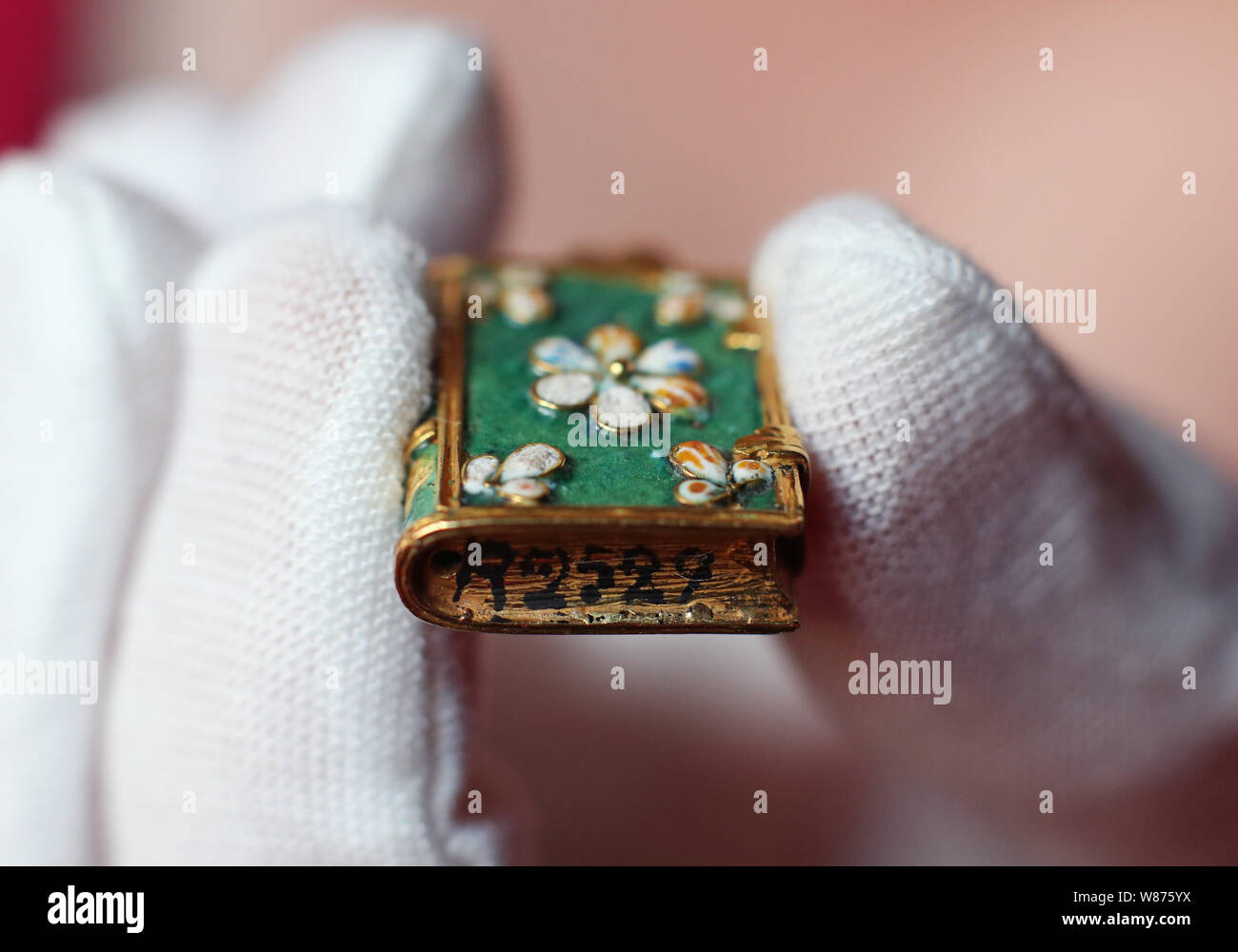 Ein gold und Emaille Anhänger (c.1640-1660) in der Form des Buches, die mit einem Nazi Inventarnummer auf dem Buch Kante, angewendet werden, wenn diese von der Französischen Rothschilds während des Zweiten Weltkriegs beschlagnahmt wurden, Waddesdon Manor, Buckinghamshire, vor der Eröffnung einer Rothschild Treasury Ausstellung, die in eine neue, dauerhafte, Galerie mit mehr als 300 selten gesehene Objekte über zwei Jahrtausende - von einem 1.-Jahrhundert Kamee des Augustus Caesar's Enkel, über Schmuck, Geschenke von Königin Victoria, um Objekte Lager NS-Inventarnummern gehalten wird. Stockfoto