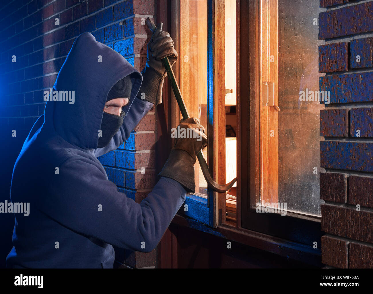 Einbrecher in ein Haus, das durch die Fenster mit einem Brecheisen Stockfoto