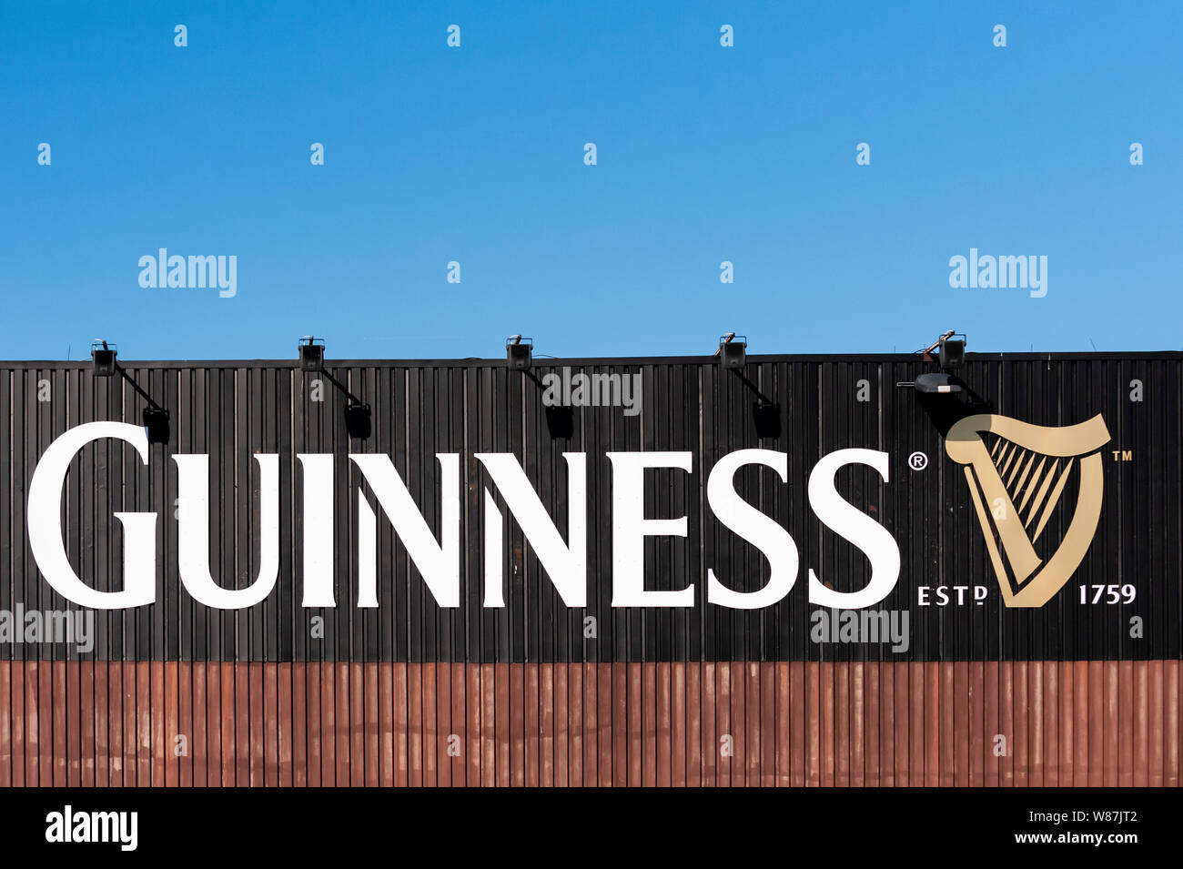 Guinness Zeichen außerhalb einer Fabrik. Blauer Himmel und Kopieren. Stockfoto