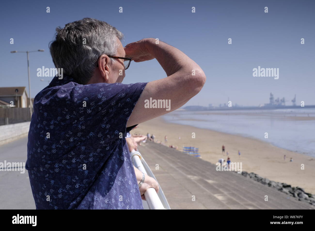 80-jähriger Mann mit Blick auf das Meer und genießt den Ruhestand am Strand bei schönem Wetter Stockfoto