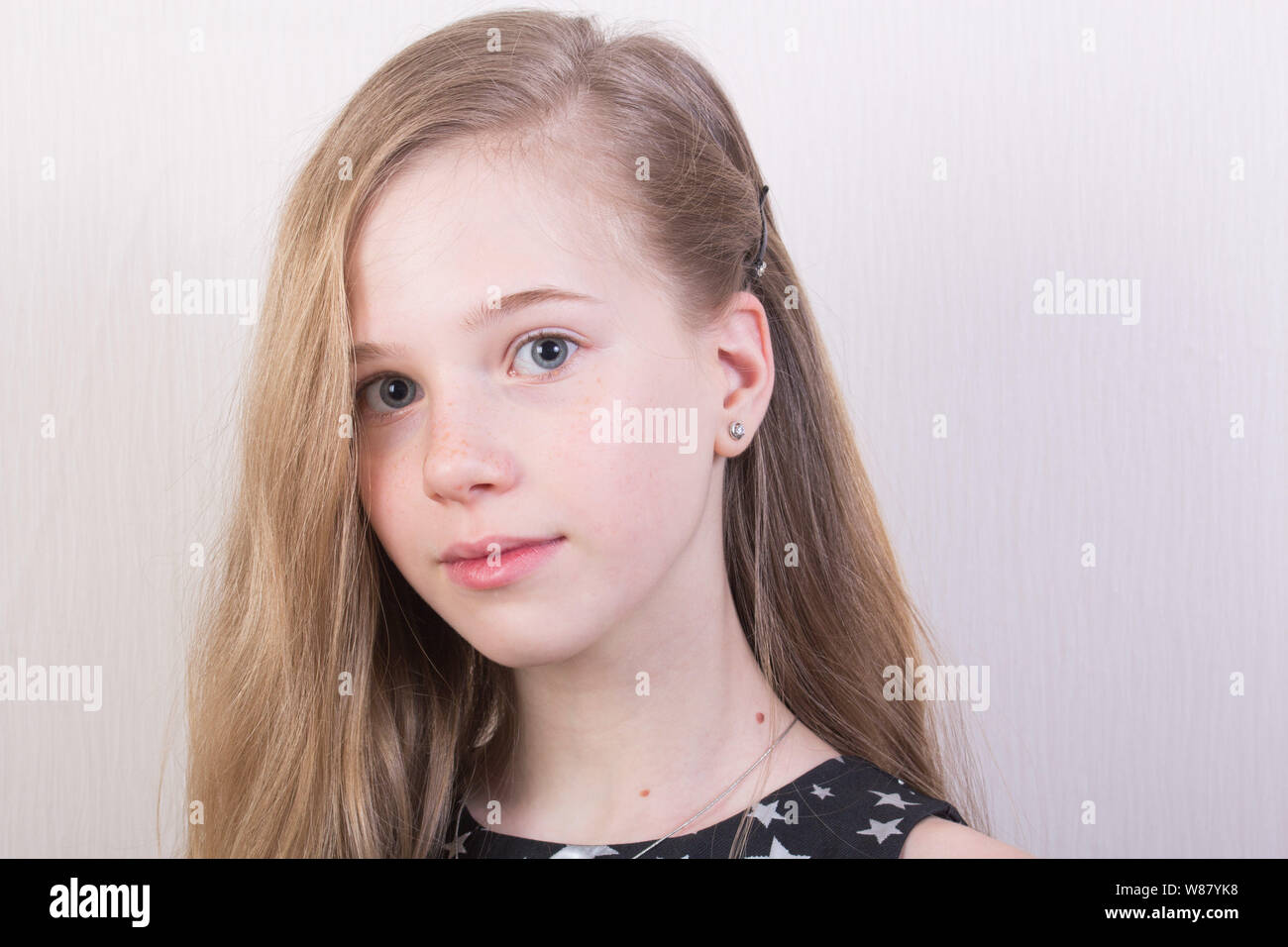 Porträt eines jungen Mädchens mit hellbraunem Haar in einem schwarzen Kleid mit silbernen Sternen. Schöne Mädchen Stockfoto