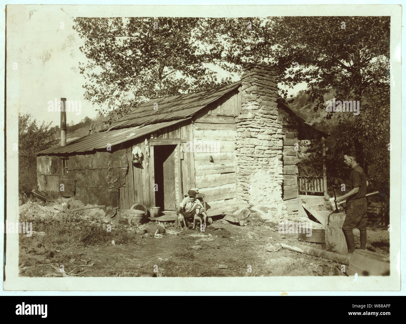 Eine kleine Blockhütte, - Relikt der alten Tage,- jetzt von einer kleinen Familie besetzt (F. T. in der Burg), die nach und nach Aufgeben der Landwirtschaft und je nach Bergbau und Gelegenheitsjobs. Okt. 12, 1921. (Hunde). Stockfoto