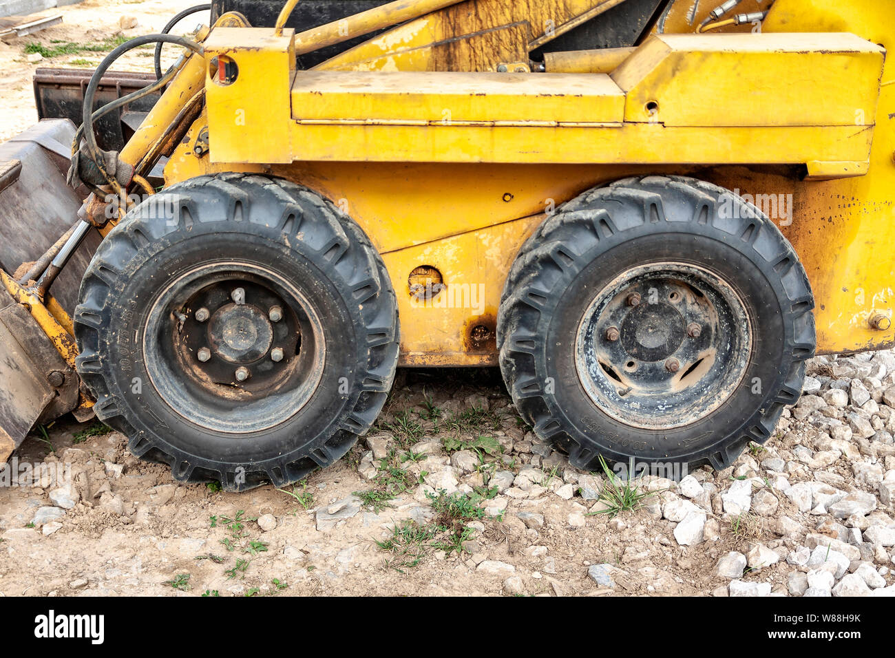 Nahaufnahme eines gelben Minibaggerrads auf einer Baustelle Stockfoto