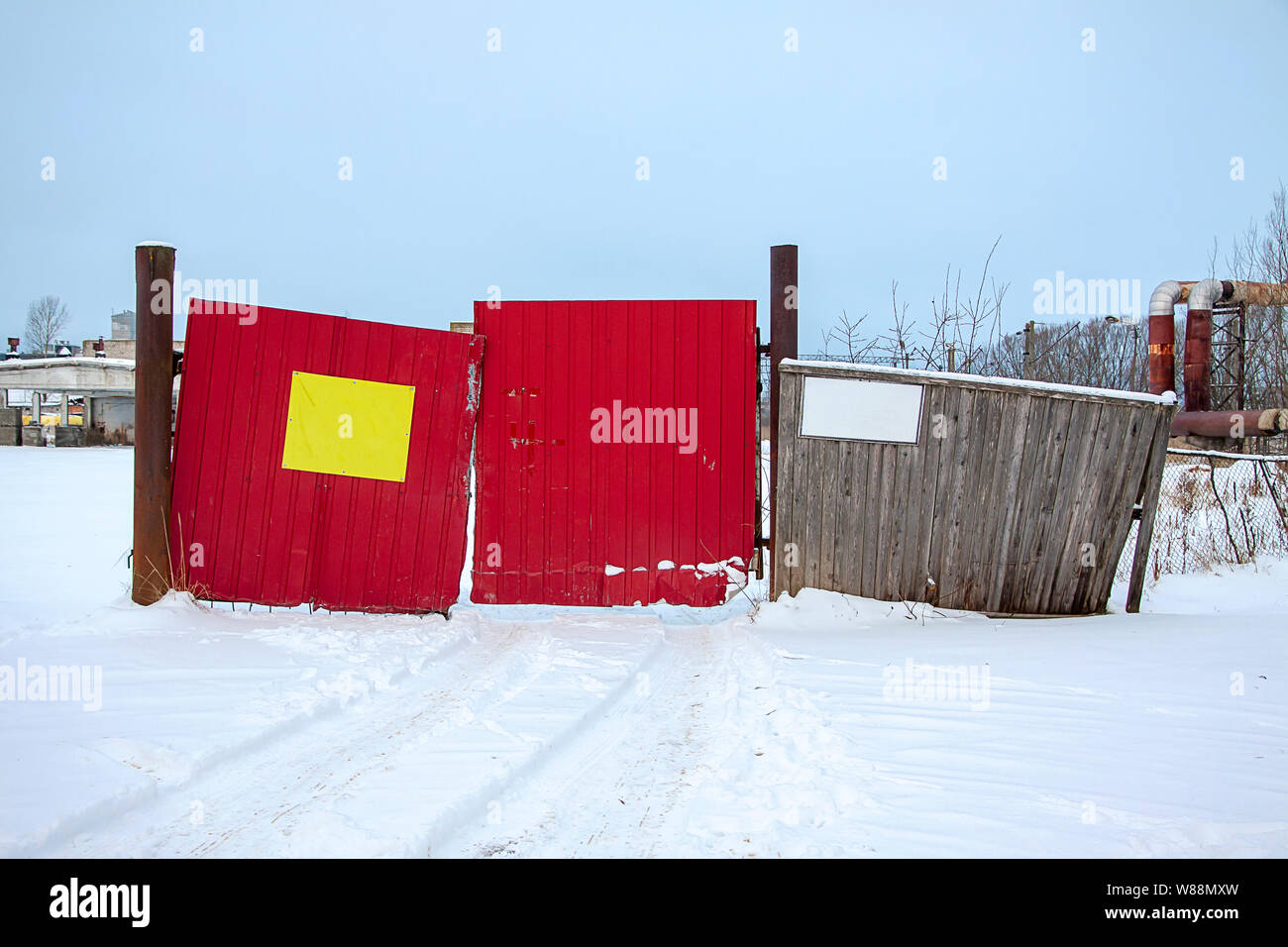 Alte Tor mit einem zerstörten Holzzaun in einem verlassenen Unternehmen. Zwei Vorlagen für Inschriften. Stockfoto