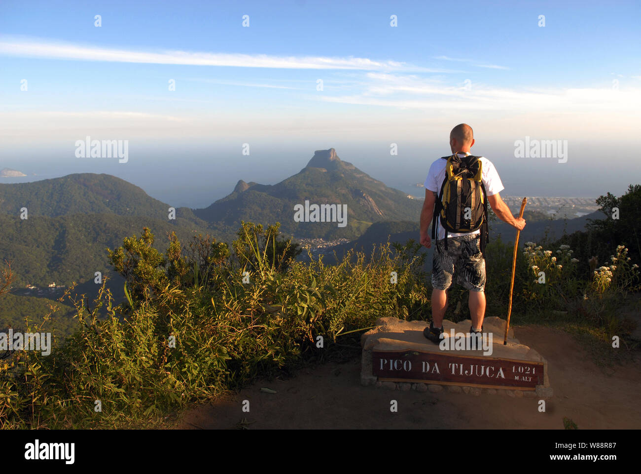 Mann in der Spitze der Pico da Tijuca, im Tijuca Nationalpark beobachtet die Ansicht von Pedra da gávea in der Stadt Rio de Janeiro Stockfoto