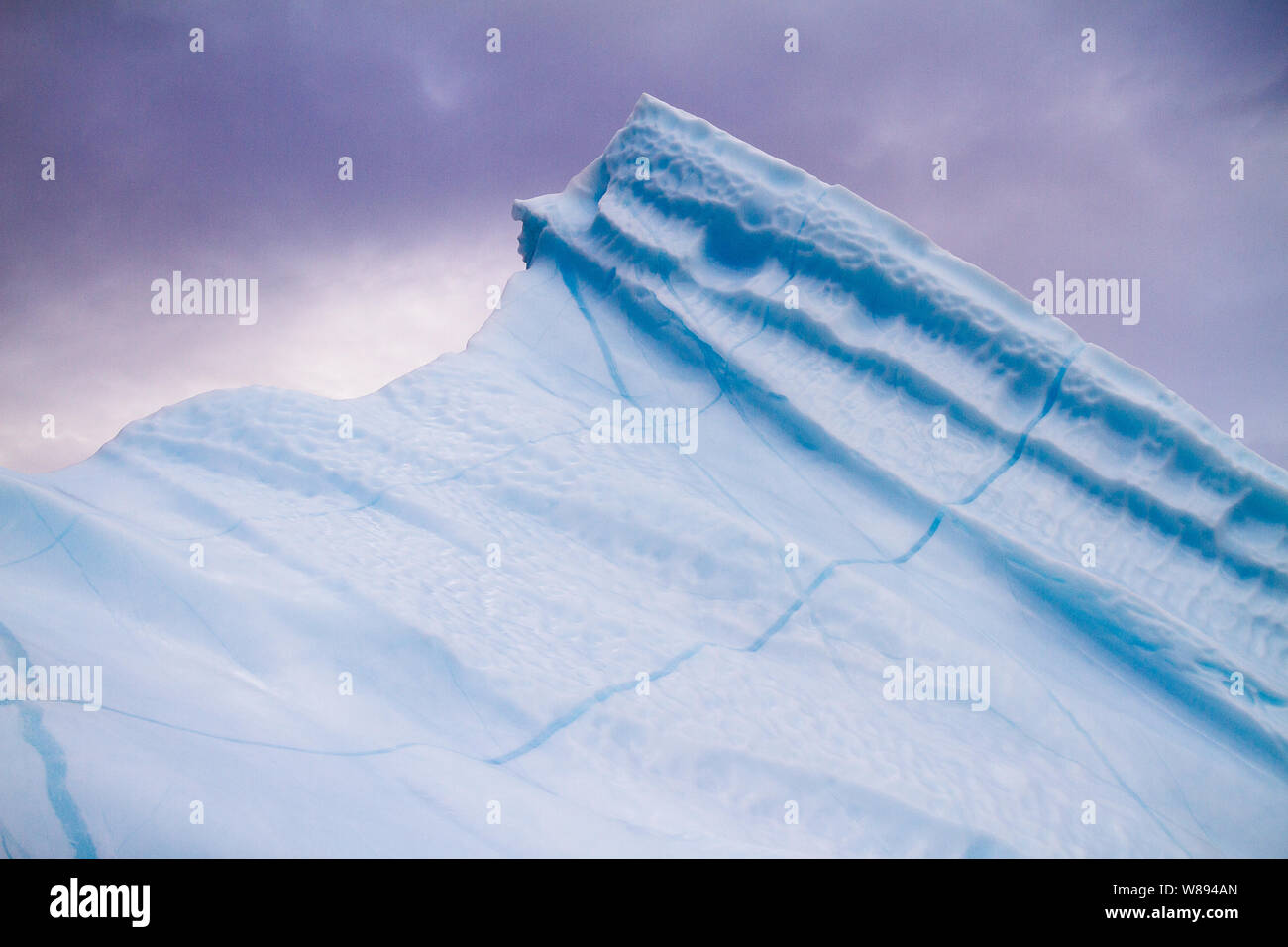 Gen Himmel mit Blick auf die Spitze des Eisberges von einem Zodiac gab mir dieser Schuss von der blauen Eis gegen die lila Himmel von Renbugten erfasst, Kaiser Franz Joseph Fjord, Grönland Stockfoto