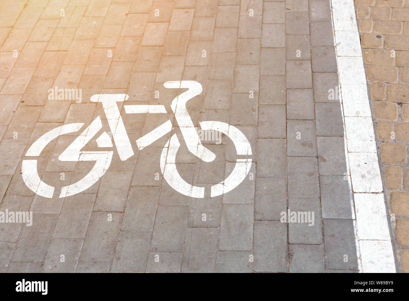 Fahrrad slab gepflasterte Gasse in der Fußgängerzone entfernt. Bike Symbol mit weißer Farbe auf Grau gepflasterten Straße bemalt. Radfahren Infrastruktur in der Stadt Stockfoto