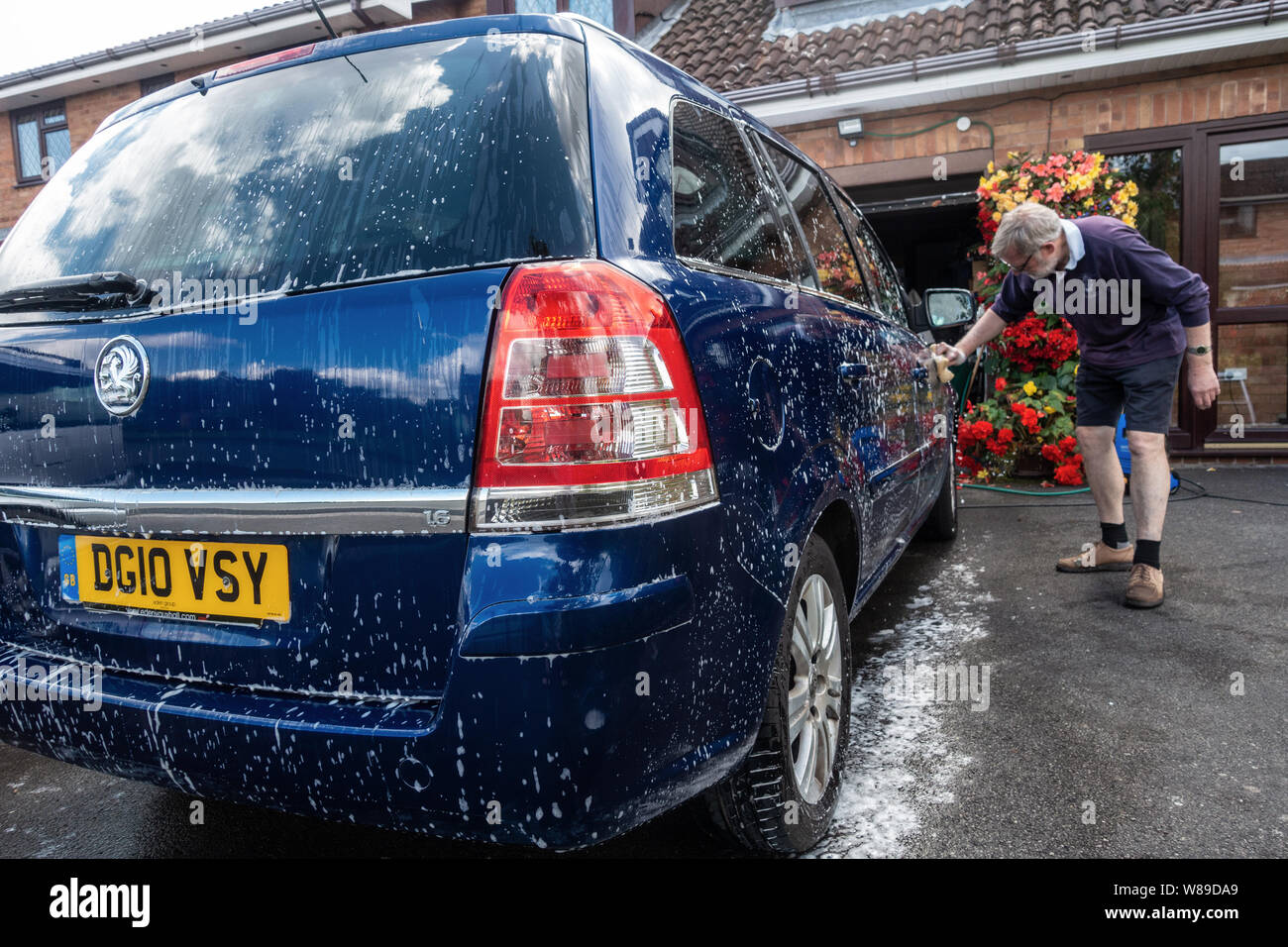 Ein Mann Hand wäscht ein Auto mit einem Schwamm und Seifenlauge. Stockfoto