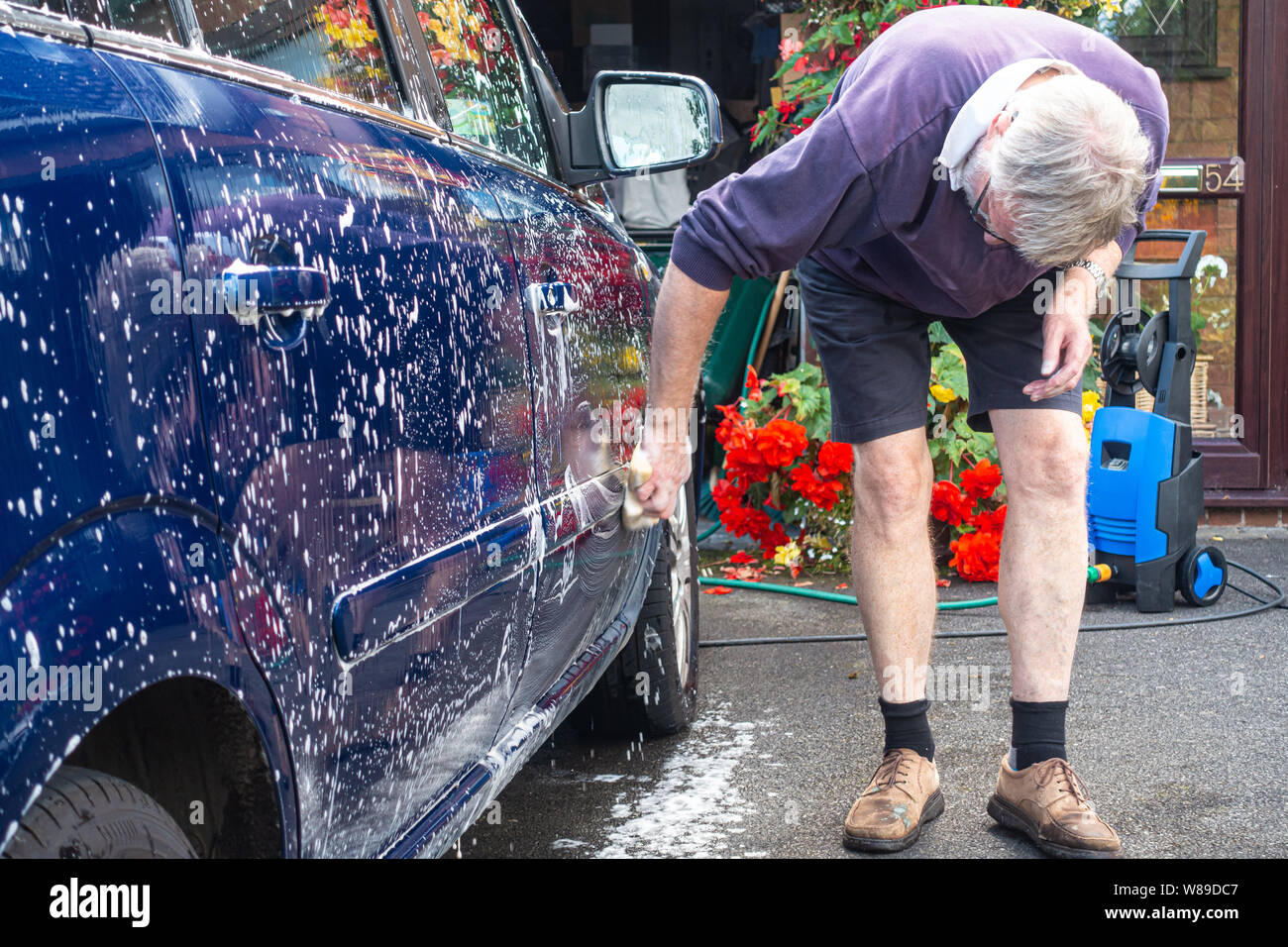 Ein Mann Hand wäscht ein Auto mit einem Schwamm und Seifenlauge. Stockfoto