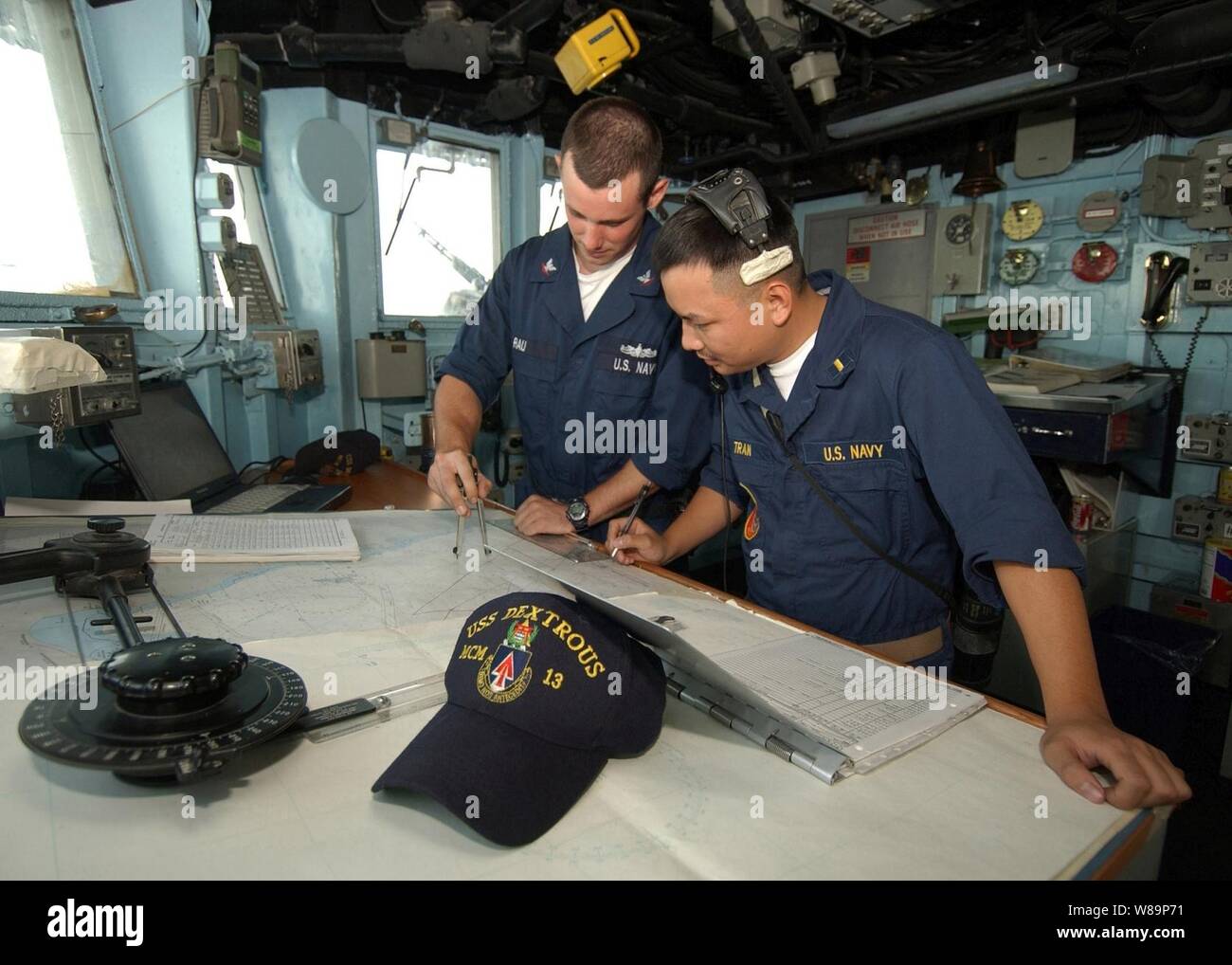 U.S. Navy Petty Officer 3rd class Seth Rau (links) und Fähnrich Zinn Tran, einen neuen Kurs Grundstück auf der Navigationskarte im Pilot House an Bord der USS geschickt (MCM 13) im Persischen Golf am 29. Juli 2004. Die Rechtsgewundenen ist einer der Avenger Klasse meine Gegenmaßnahmen Schiffe der Marine. Stockfoto