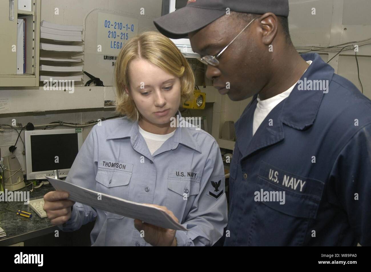 Petty Officer 3rd class Candie Thompson (links), von der USS Kitty Hawk (CV 63) Rechtsbeistand, Vorlagen Feuerwehrmann Paul Byrd beim Ausfüllen einer briefwahl am Okt. 13, 2004. Abwesende Stimmzettel sichergestellt, dass alle militärischen Mitglieder im Ausland stationiert sind, um die Möglichkeit zu wählen. Byrd serviert an Bord der Kitty Hawk als Rumpf Wartungstechniker. Stockfoto Petty Officer 3rd class Candie Thompson (links), von der USS Kitty Hawk (CV 63) Rechtsbeistand, Vorlagen Feuerwehrmann Paul Byrd beim Ausfüllen einer briefwahl am Okt. 13, 2004. Abwesende Stimmzettel sichergestellt, dass alle militärischen Mitglieder im Ausland stationiert sind, um die Möglichkeit zu wählen. Byrd serviert an Bord der Kitty Hawk als Rumpf Wartungstechniker. Stockfoto