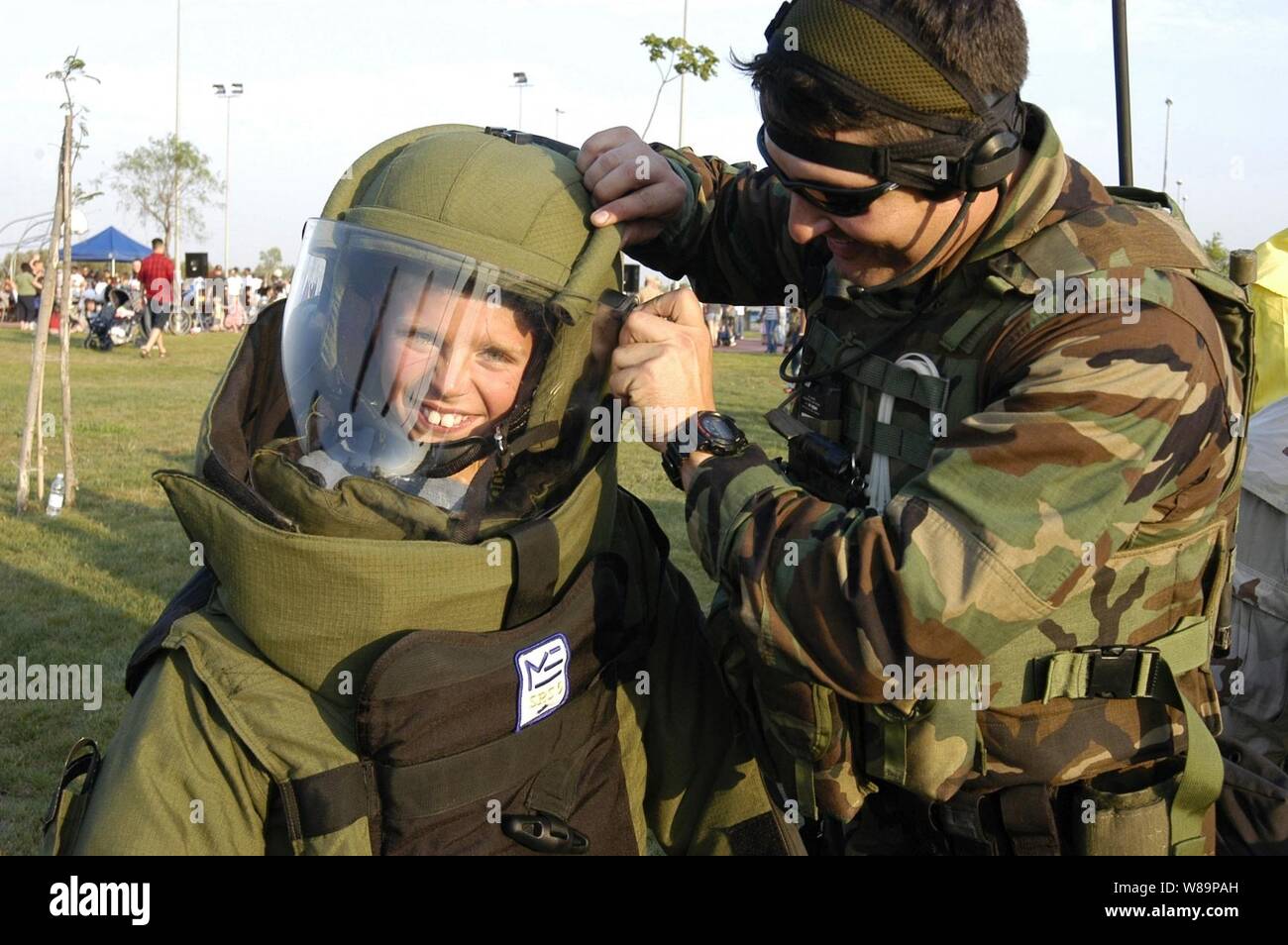 Ein Junge grinst durch den Gesichtsschutz Helm, wie er ist, in eine Beseitigung von Explosivstoffen Anzug auf der 21. jährlichen Nationalen Abend Veranstaltung im marinai Gehäuse Community Center, Naval Air Station Sigonella, Sizilien, am Aug 3, 2004 gehalten. Naval Air Station Sigonella bietet logistische Unterstützung für Commander, der Sechsten Flotte und der Nordatlantikvertrags-organisation Kräfte im Mittelmeerraum. Stockfoto