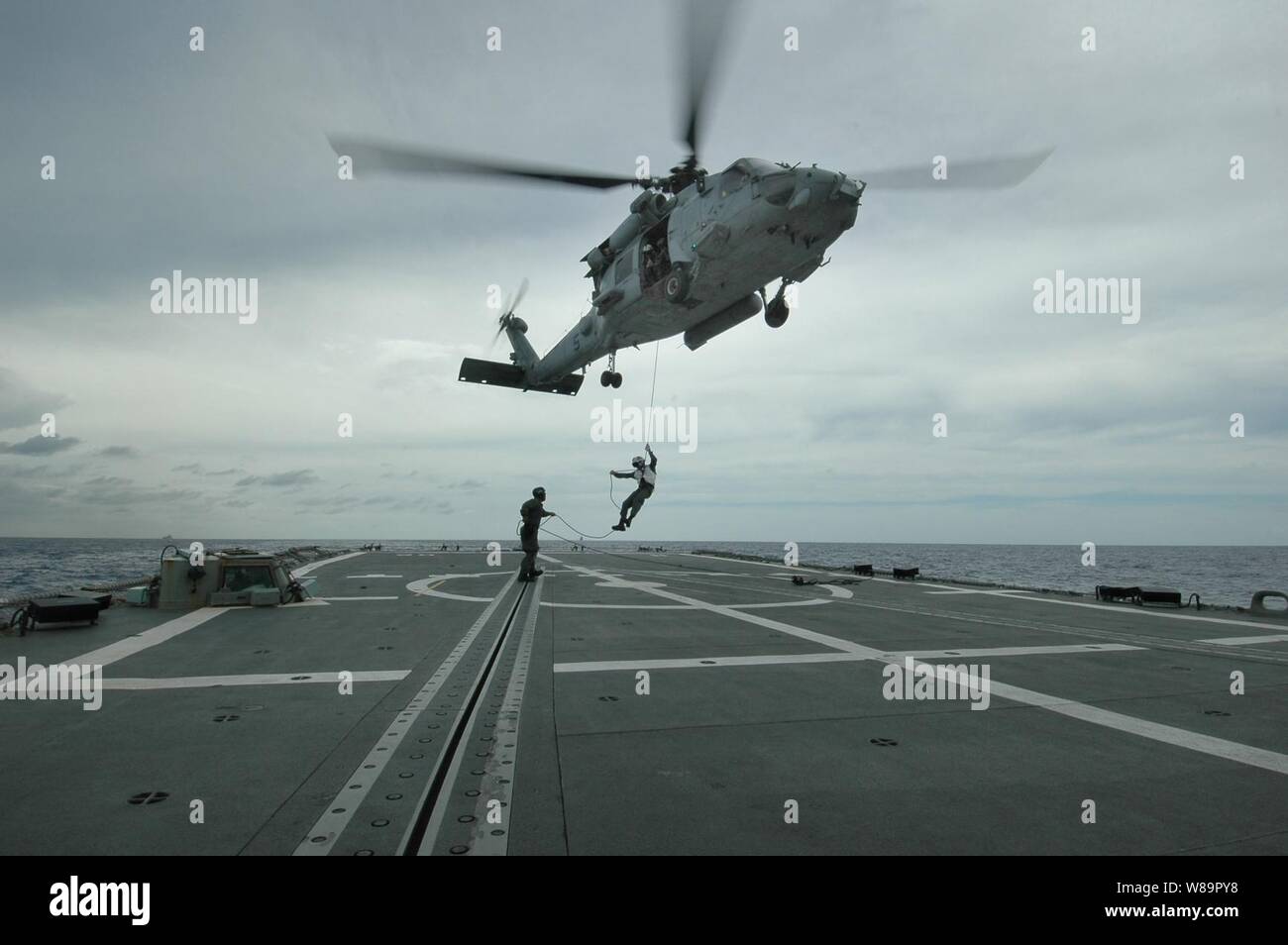 Ein U.S. Navy HH-60H Seahawk Hubschrauber schwebt über dem Flight Deck der HMAS Canberra (FFG 02) Als während der Adm. Jamie D. Kelly, Kommandeur der Carrier Strike Group 5, rappels auf das Deck am 7. Juni 2005. Kelly ist zu Besuch in Canberra vor (CV 63) Beteiligung der Flugzeugträger USS Kitty Hawk in der Übung Talisman Sabre, alle zwei Jahre einen gemeinsamen Kräfte und kombinierte Übung mit der australischen Marine. Stockfoto