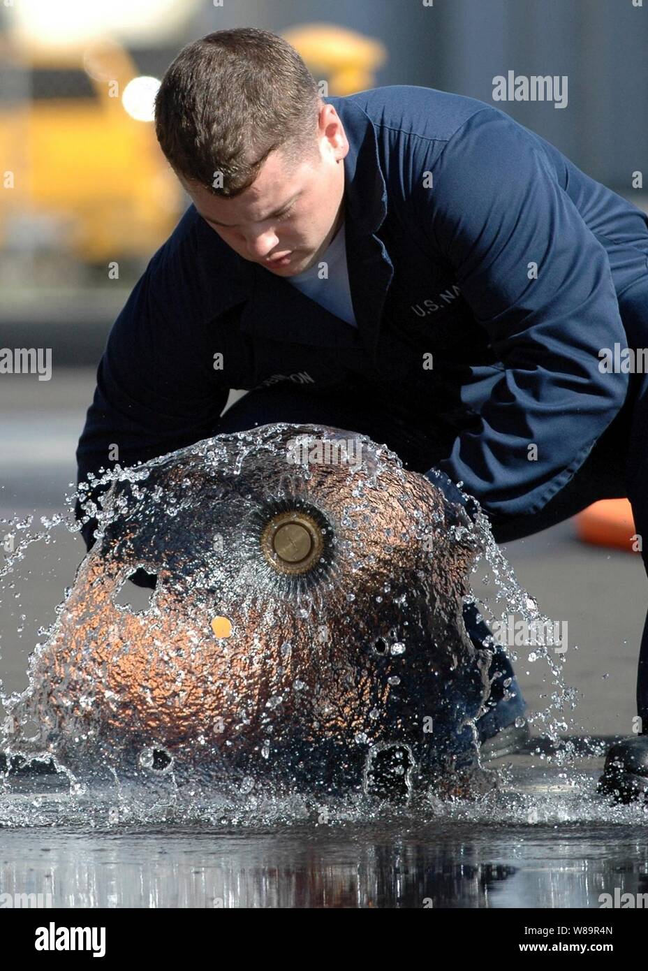 U.S. Navy Schäden Controlman Feuerwehrmann Jason Robinson öffnet sich die Düse eines Brandes Schlauch während der Schadensbegrenzung Olympics in Pearl Harbor, Hawaii, am 6 Okt., 2005. Robinson ist der Lenkwaffen-zerstörer USS Paul Hamilton (DDG60) zugeordnet. Stockfoto