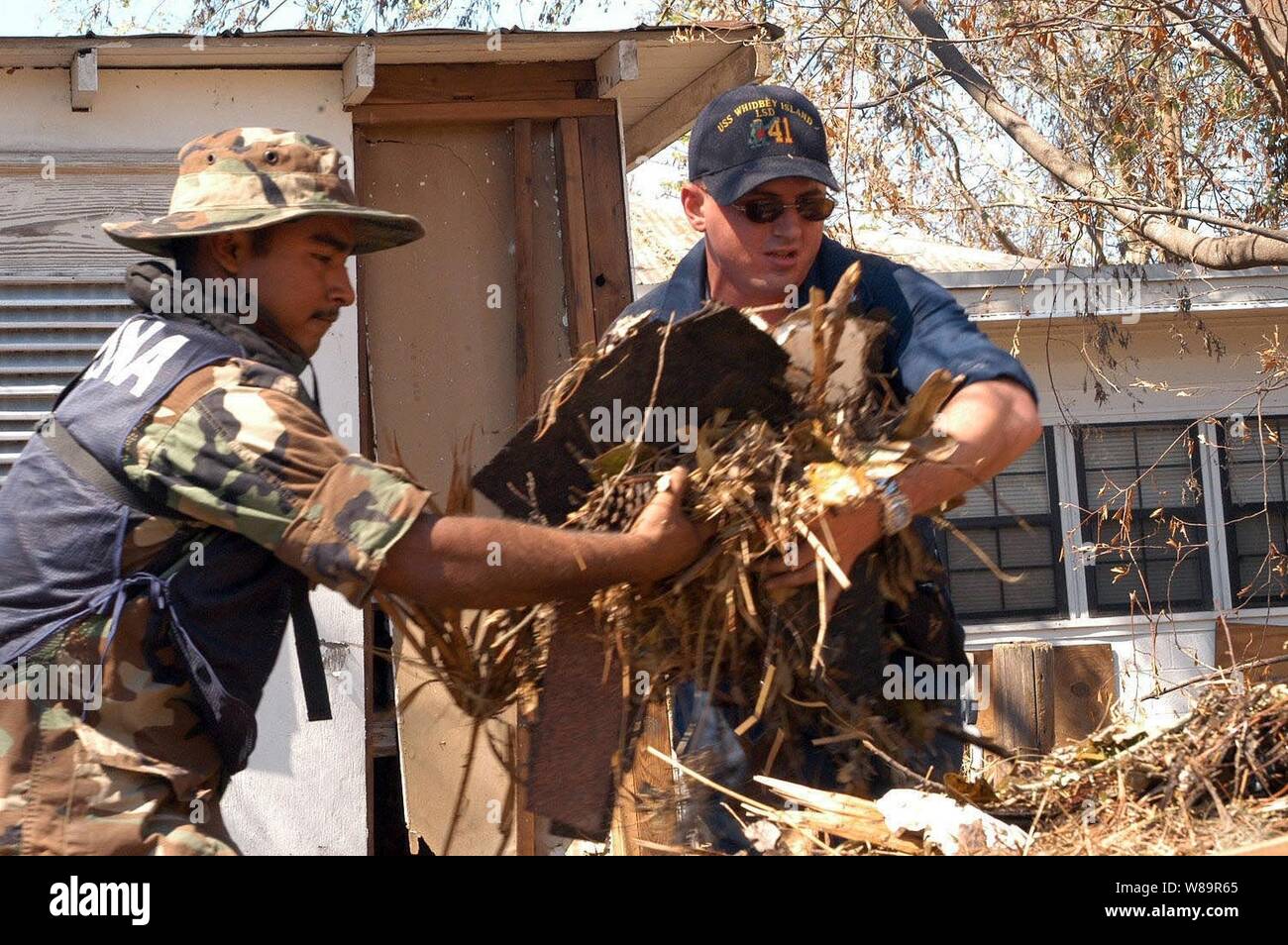 Segler aus der mexikanischen Marine und US-Navy arbeiten zusammen, um Rückstände von einem Haus in Biloxi, Fräulein, Sept. 11, 2005. Die mexikanische Marine ist die Unterstützung der US-Marine bei der Bereitstellung humanitärer Hilfe für die Opfer von Hurrikan Katrina. Departement für Verteidigung Einheiten werden als Teil der Gemeinsamen Task Force Katrina mobilisiert Katastrophenhilfe der Federal Emergency Management Agency in der Gulf Coast Bereiche, die durch Hurrikan Katrina verwüstet zu unterstützen. Stockfoto