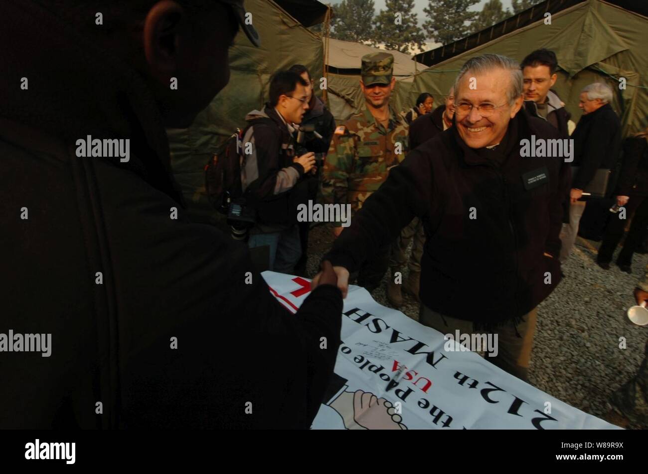 Verteidigungsminister Donald H. Rumsfeld reicht die Hand eines Soldaten zu schütteln, weil er grüßt US-Army Soldaten in die 212Th Mobile Army Surgical Hospital in Muzaffarabad, Pakistan zugeordnet, auf Dez. 21, 2005. Rumsfeld ist ein Besuch der Bereiche, die vom 8. Oktober 2005, Erdbeben beschädigt und Treffen mit dem US-Personal, den Überlebenden zu helfen. Stockfoto