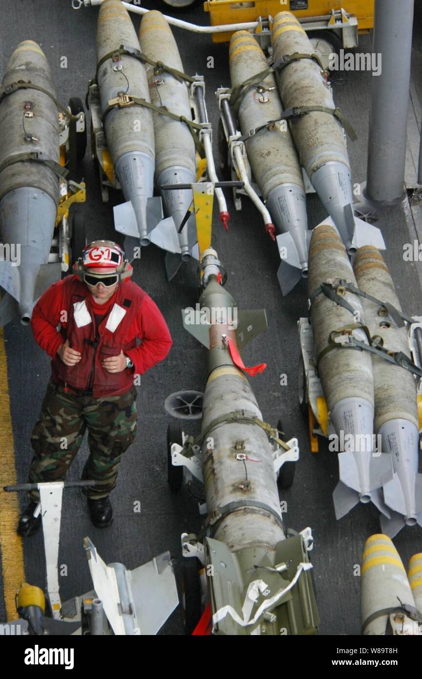 Eine Marine ordnanceman steht Wache über Bomben positioniert auf dem Flugdeck der Flugzeugträger USS Kitty Hawk (CV 63) als das Schiff führt den Flugbetrieb im philippinischen Meer am 15. Juni 2006. Stockfoto