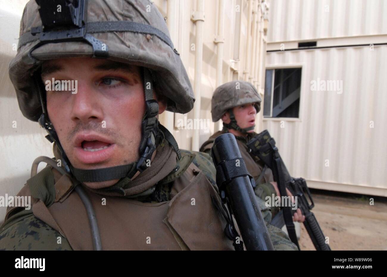 Ein US-Marine aus dem 3. Marine Expeditionary Brigade Kollegen um die Ecke eines Gebäudes während der Verteidigung Camp Himbeere von australischen Soldaten während der Übung Talisman Sabre 2007 an der Shoalwater Bay Ausbildung Gebiet in Queensland, Australien, am 26. Juni 2007. Camp Himbeere ist eine simulierte Stadt service Mitglieder zu trainieren, wie sie in einer städtischen Umgebung betrieben werden. Die alle zwei Jahre stattfindende Übung ist so konzipiert, australischen und US-Streitkräfte in die Planung und Durchführung der Kombinierten task force Operationen, die Bekämpfung der Bereitschaft und der Verbesserung der Interoperabilität. Stockfoto