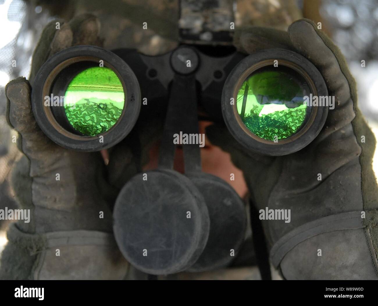 Us-Armee SPC. John Galebach verwendet Fernglas den Horizont stehend hinten Air Guard auf einem Stryker Fahrzeug in Baqubah, Irak, am 19. Juni 2007 zu scannen. Galebach ist Charlie Company, 2.BATAILLON, 1 Infanterie Regiment, 3. Brigade Combat Team, 2 Infanterie Division zugeordnet. Stockfoto