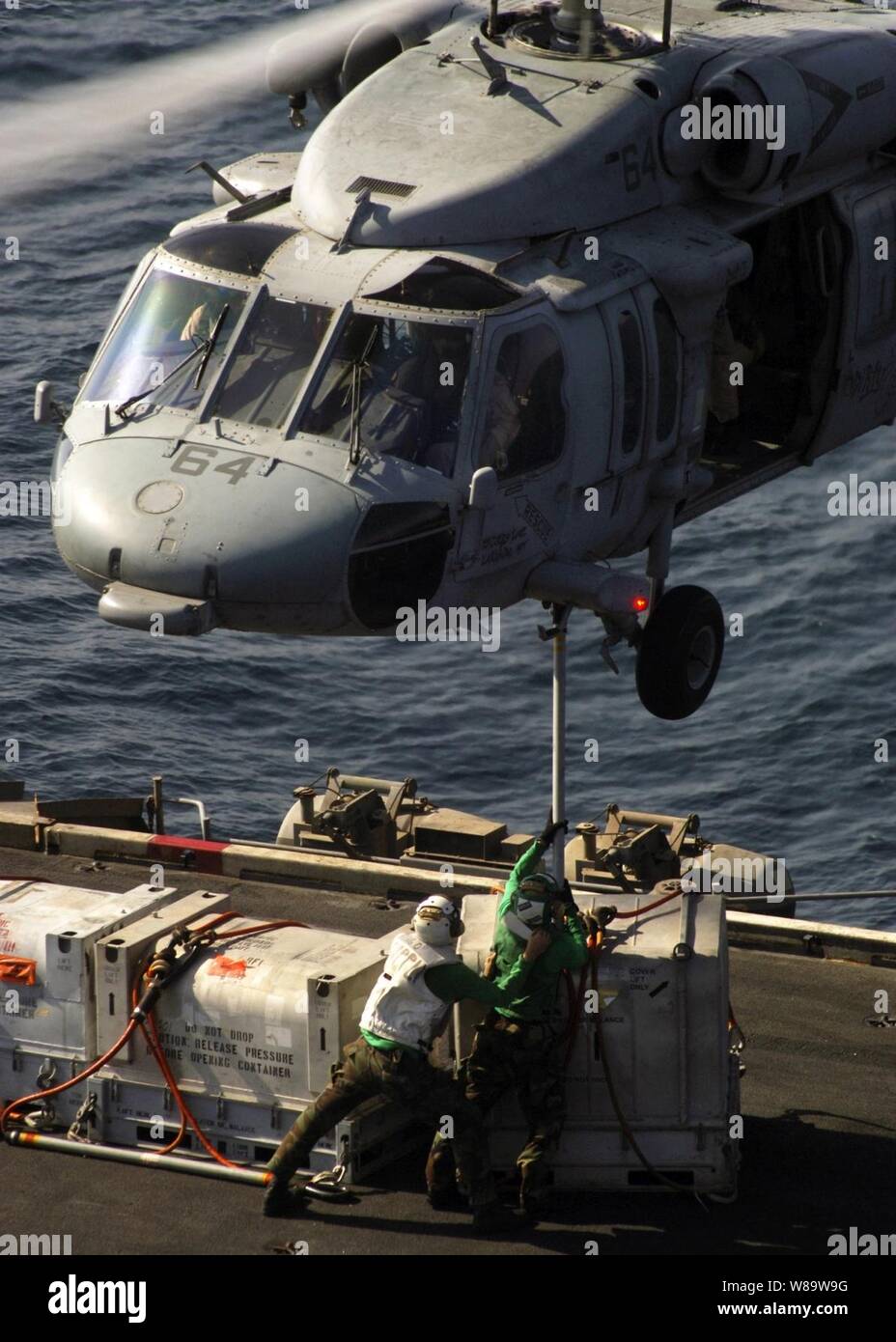 U.S. Navy Matrosen an Bord des Atom-Flugzeugträger USS Enterprise (CVN 65) hook up Cargo in den Bauch der einem MH-60S Seahawk Hubschrauber während eine Auffüll-anforderung auf See mit der Military Sealift Command schnell Combat support ship USNS (T-AOE6) während der Fahrt im Persischen Golf am Okt. 28, 2007. Stockfoto