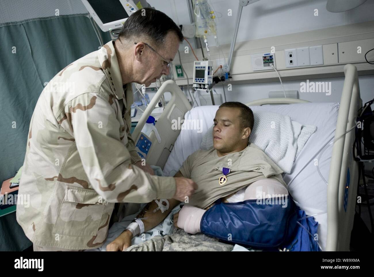 Vorsitzende des Generalstabs Adm. Mike Mullen, U.S. Navy, Auszeichnungen die Lila Herz US-Armee Sgt. Marcus Liebe auf den Luftwaffenstützpunkt Bagram, Afghanistan, die früher am Tag am 14. Juli 2009 verwundet wurde. Liebe ist auf den 3. Brigade, 10 Mountain Bereich zugeordnet. Mullen ist die Begleitung eines USO-Tour mit Hall of Fame NFL Coach Don Shula, NFL zurück laufen Warrick Dunn, Schauspieler Bradley Cooper und D.B. Sweeney und Sport Persönlichkeit und Modell Leeann Tweeden bei einem Besuch der zentrale Bereich der Verantwortung. Stockfoto