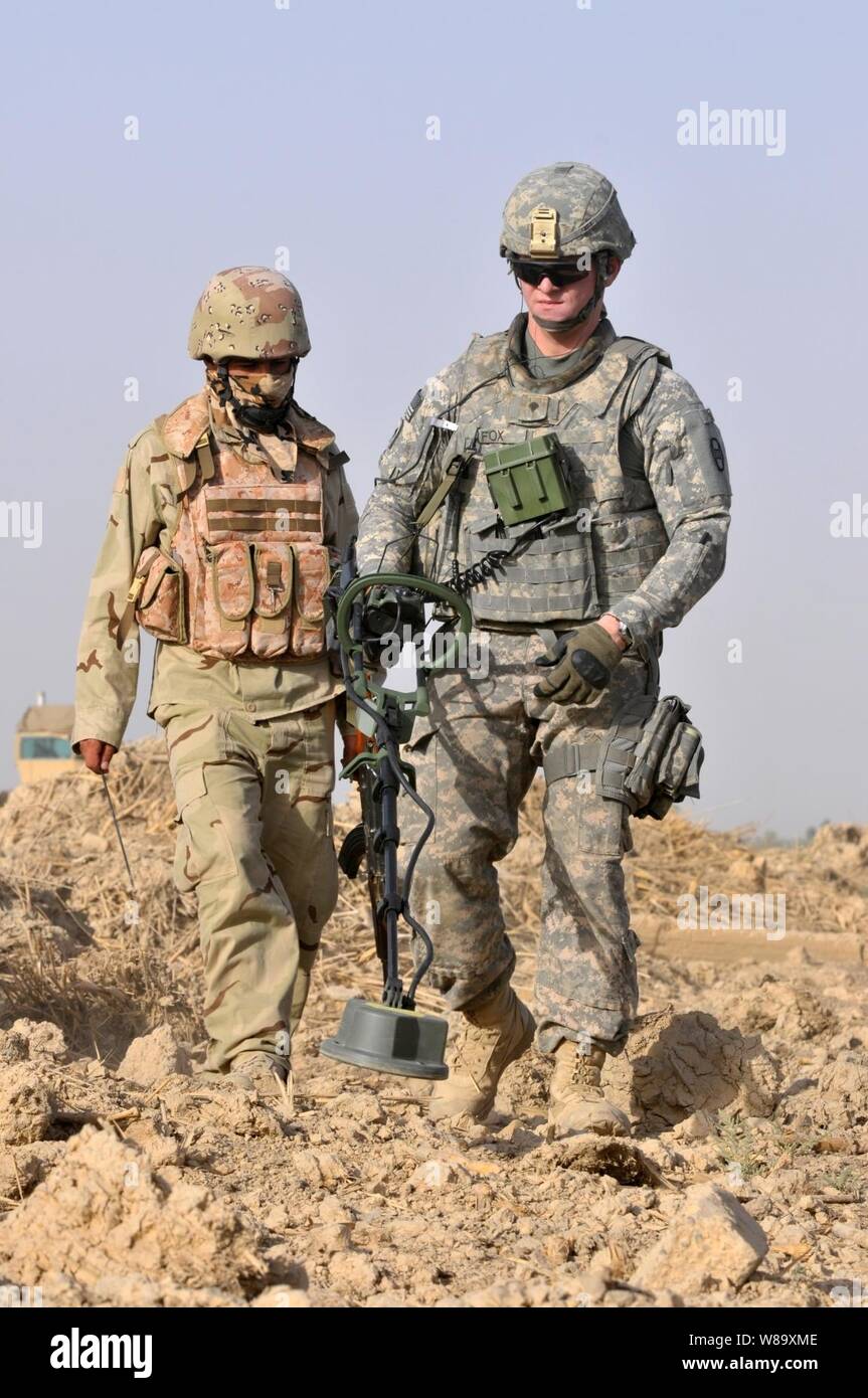 Die US-Armee Soldaten mit 1 Platoon, Comanche Truppe, 1.Staffel, 150 Cavalry Regiment, 30 Heavy Brigade Combat Team, 1.Kavallerie Division hilft irakischen Soldaten mit 1., 3., 23., 17. irakischen Division führen Waffen cache sucht durch offene Felder in der radwaniyah Bereich außerhalb von Bagdad, Irak, am 18. Juli 2009. Stockfoto