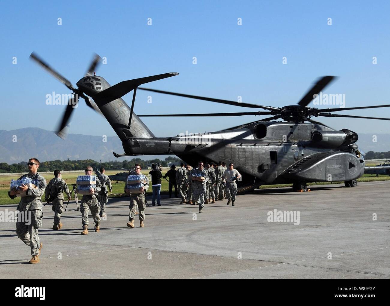 Us-Armee Soldaten entladen und Lebensmitteln aus einem Navy MH-53E Sea Dragon Helikopter aus dem Flugzeugträger USS Carl Vinson (CVN 70) auf dem Flughafen von Port-au-Prince, Haiti, Jan. 15, 2010. Das US-Militär ist die Durchführung von humanitären und Katastrophenhilfe nach einem 7,0-Erdbeben verursacht schwere Schäden in und um Port-au-Prince am Jan. 12, 2010. Stockfoto