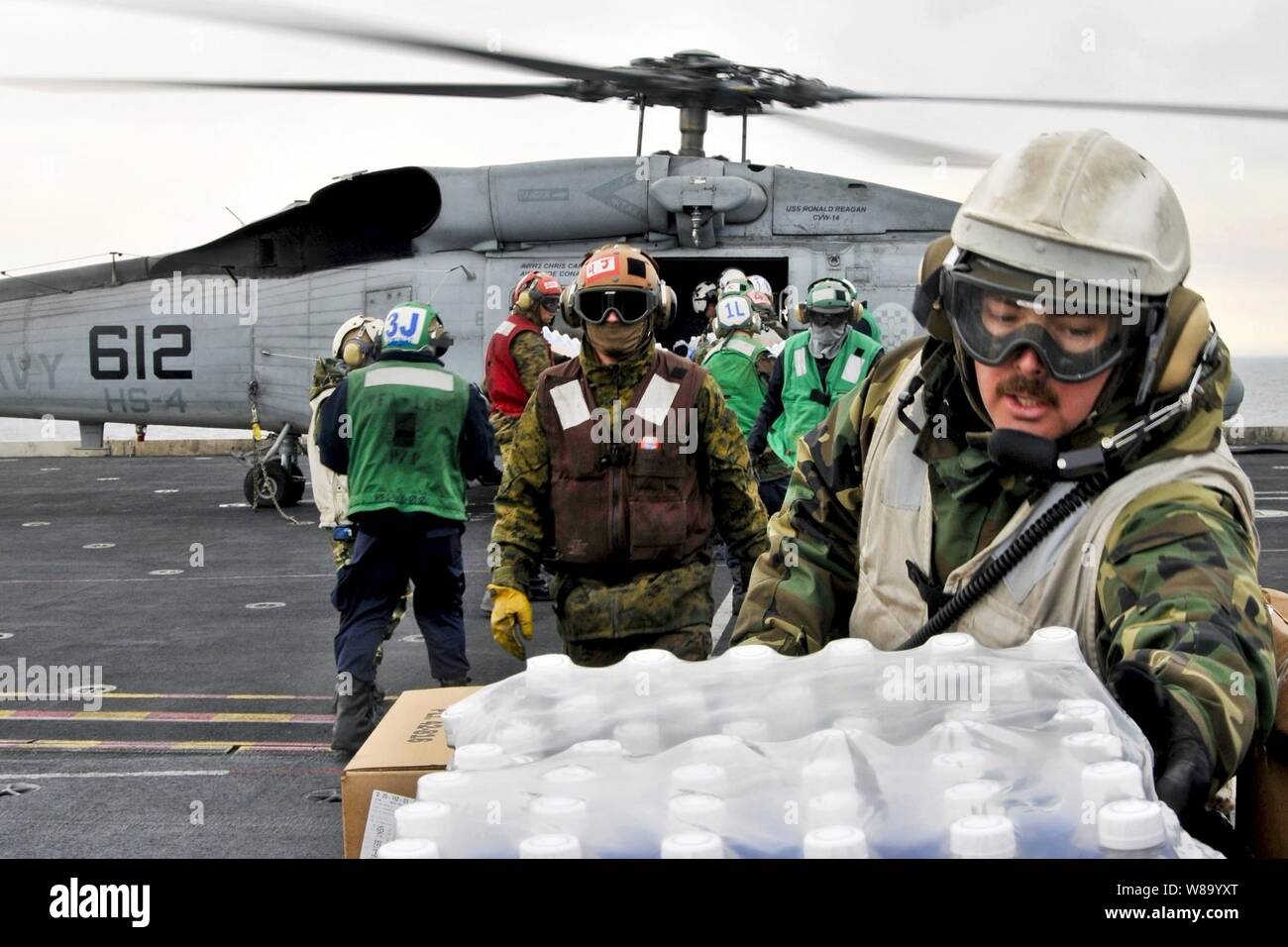 Us-Matrosen und Marines an Bord der Flugzeugträger USS Ronald Reagan Last humanitäre Hilfe liefert auf ein HH-60 UHR Seahawk Hubschrauber Anti-Submarine Squadron 4 im Pazifischen Ozean zugewiesen wurde am 19. März 2011. Der Ronald Reagan ist vor der Küste von Japan, die humanitäre Hilfe zu unterstützen Betrieb Tomodachi. Stockfoto