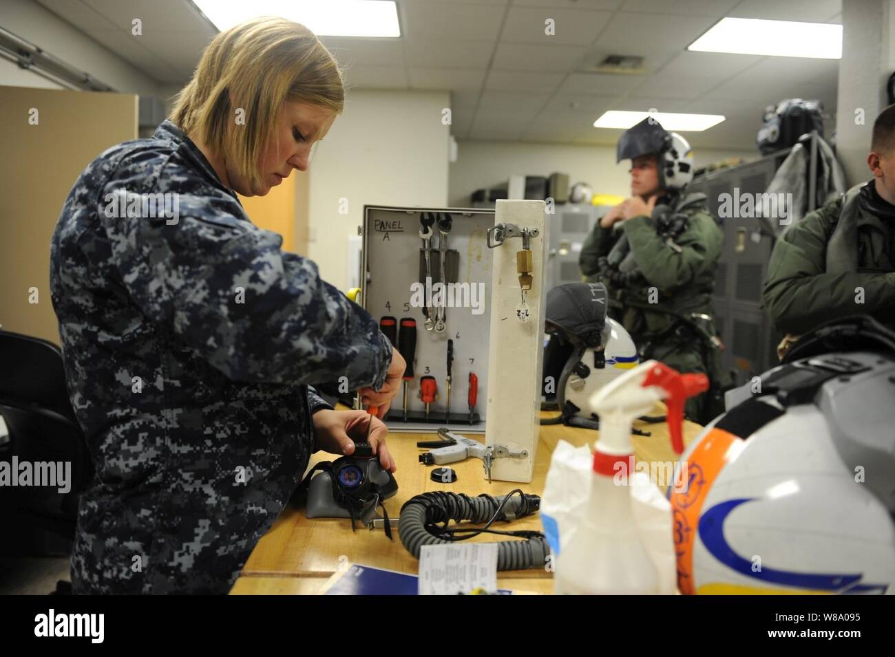 U.S. Navy Airman Jessica Tescher (links), einen Fallschirm Rigger, führt eine monatliche Wartung prüfen, auf der ein Pilot Helm während der Übung der nördlichen Flanke am Joint Base Elmendorf-Richardson, Alaska, am 16. Juni 2011. Nördlichen Rand ist eine jährliche gemeinsame Ausbildung Übung für militärische und zivile Reaktion und Koordination Fähigkeiten, während gleichzeitig das Kommando, Kontrolle und Kommunikation Beziehungen mit gemeinsamen Aktionen zu testen. Stockfoto