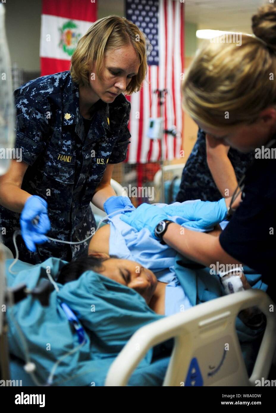 Us Navy Lieutenant Cmdr. Marsha Hanly (links) macht einen Patienten in der Intensivstation an Bord der Hospital Ship USNS Comfort (T-AH 20) in Acajutla, El Salvador, während weiterhin Versprechen 2011 am 20. Juli 2011 komfortabel. Weiterhin Versprechen ist ein regelmäßig geplante Mission zu Ländern in Mittel- und Südamerika und in der Karibik, wo die US-Marine und ihre Zusammenarbeit mit dem Host Nationen Nationen arbeiten und eine Vielzahl von staatlichen und nichtstaatlichen Einrichtungen in zivil-militärischen Operationen zu trainieren. Stockfoto