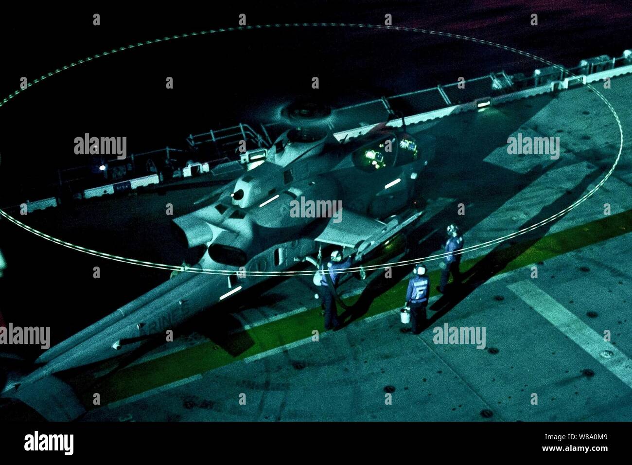 U.S. Navy sailors Verhalten die heiße Betanken eines AH-1 Cobra Kampfhubschrauber während der Nacht Flugbetrieb an Bord der USS Makin Island im Indischen Ozean am Dez. 30, 2011. Die Matrosen sind Luftfahrt boatswainís Gehilfen und die Cobra Besatzung zu Marine Medium Helicopter Squadron 268 verstärkt zugeordnet. Der Makin Island ist auf seinem Jungfernflug Bereitstellung und Durchführung von Operationen in den USA 7 Flotte Verantwortungsbereich. Stockfoto