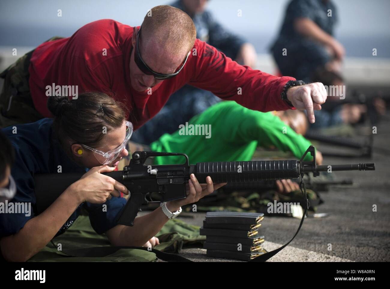 Petty Officer 1st Class Allen Lunn, eine Linie Reisebus, gibt Seaman Bretagne Koval Anleitung zum Brand einer M-16 service Gewehr während einer Live-fire gun Qualifikation Übung an Bord des amphibious Transport dock Schiff USS New Orleans LPD (18) im Arabischen Meer am 8. März 2012. Die New Orleans und schiffte sich Marines auf den 11 Marine Expeditionary Unit zugewiesen werden als Teil der Makin Island Amphibious Ready Gruppe implementiert und unterstützt die Maritime Security Operations und Theater Sicherheit Zusammenarbeit in den USA 5 Flotte Verantwortungsbereich. Stockfoto