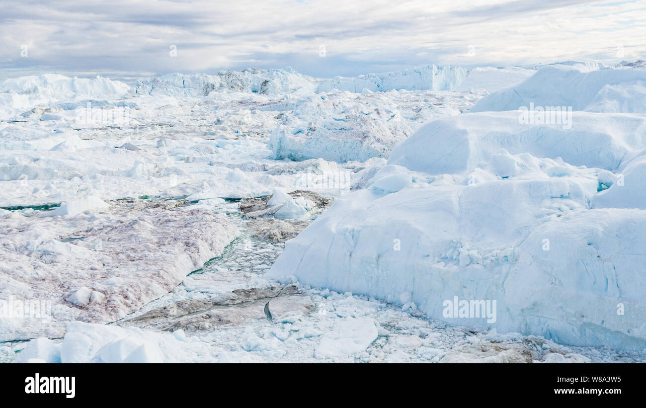 Drone Bild des Eisbergs und Eis von Gletscher in der Arktis Natur Landschaft auf Grönland. Luftbild Drohne Foto von Eisbergen in Ilulissat Eisfjord. Durch den Klimawandel und die globale Erwärmung betroffen. Stockfoto