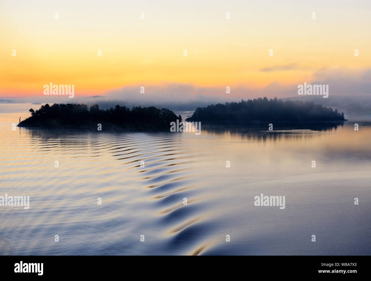 Die bewaldeten Inseln in Silhouette in den Stockholmer Schären entlang der schwedischen Küste von der Ostsee gesehen an einem nebligen Morgen schönen Sonnenaufgang. Stockfoto