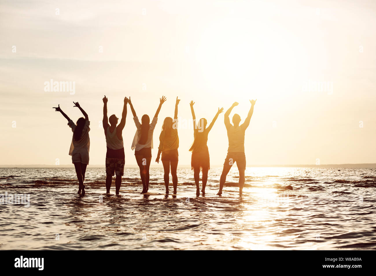Gruppe von sechs glückliche Freunde ist Spaß und Gruß Sonnenuntergang mit erhobenen Armen Stockfoto