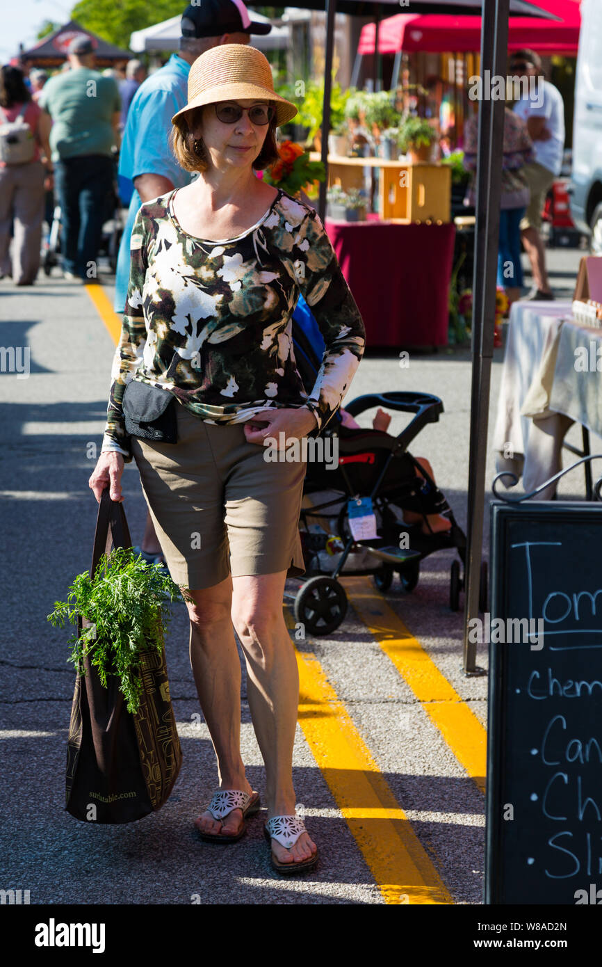 Eine edle Dame trägt ihr Kauf in ihrer Tasche beim Einkauf bei Fort Wayne's Bauernmarkt in der Innenstadt von Fort Wayne, Indiana, USA. Stockfoto