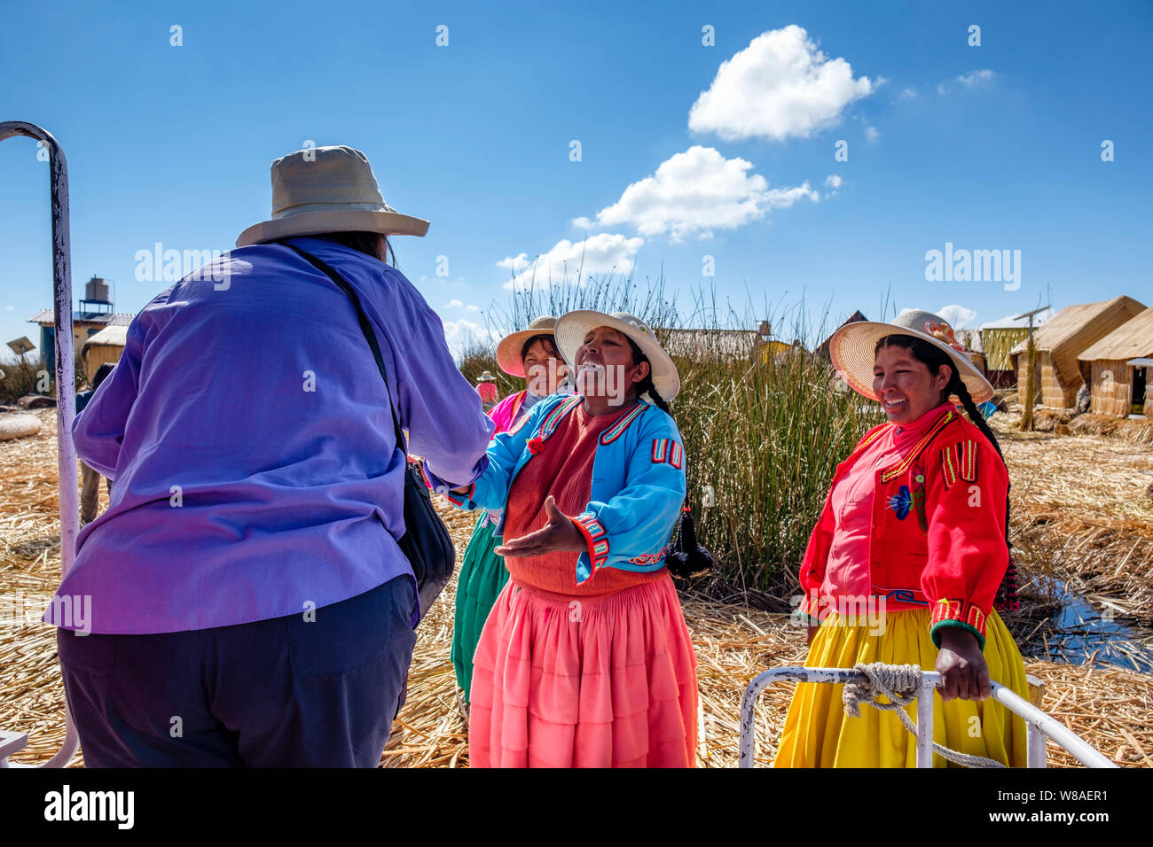 Lächelnd lokalen Uru indigenen Frauen begrüßen Touristen / Touristen auf einer Totora Schilf schwimmende Insel, Uros schwimmende Inseln, Titicaca-See, Uros, Puno, Stockfoto
