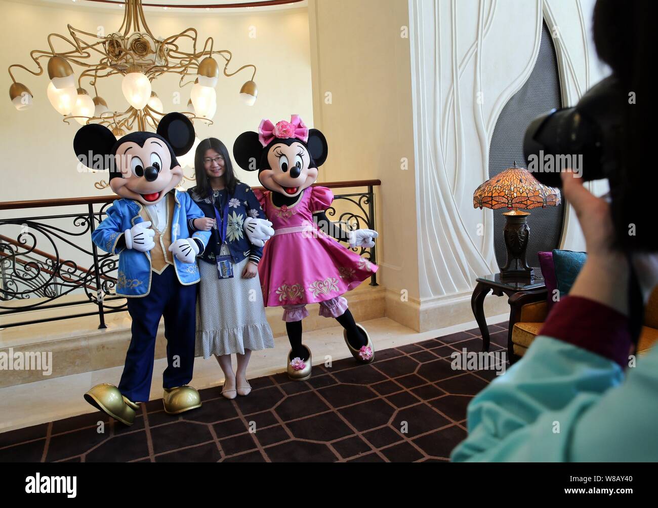 Ein Kunde stellt für Fotos mit Animateuren in Kostümen von Micky Mouse und Minnie Mouse im Shanghai Disneyland Hotel an der Shanghai Dis gekleidet Stockfoto