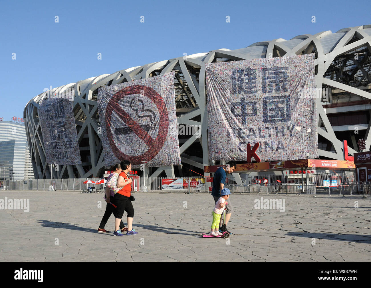 Fußgänger vorbei Anti-Rauchen Banner auf der Pekinger Nationalstadion angezeigt, auch als Bird's Nest genannt, vor der Weltnichtrauchertag in Stockfoto