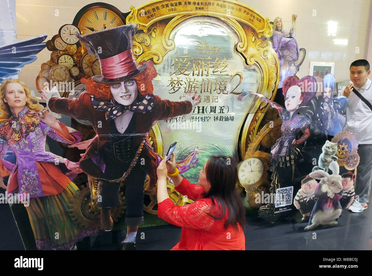 Eine Chinesische filmgoer nimmt Bilder von einem Ausschnitt Plakat des Films "Alice Through the Looking Glass" in einem Kino in Kunshan City, Central China Hube Stockfoto