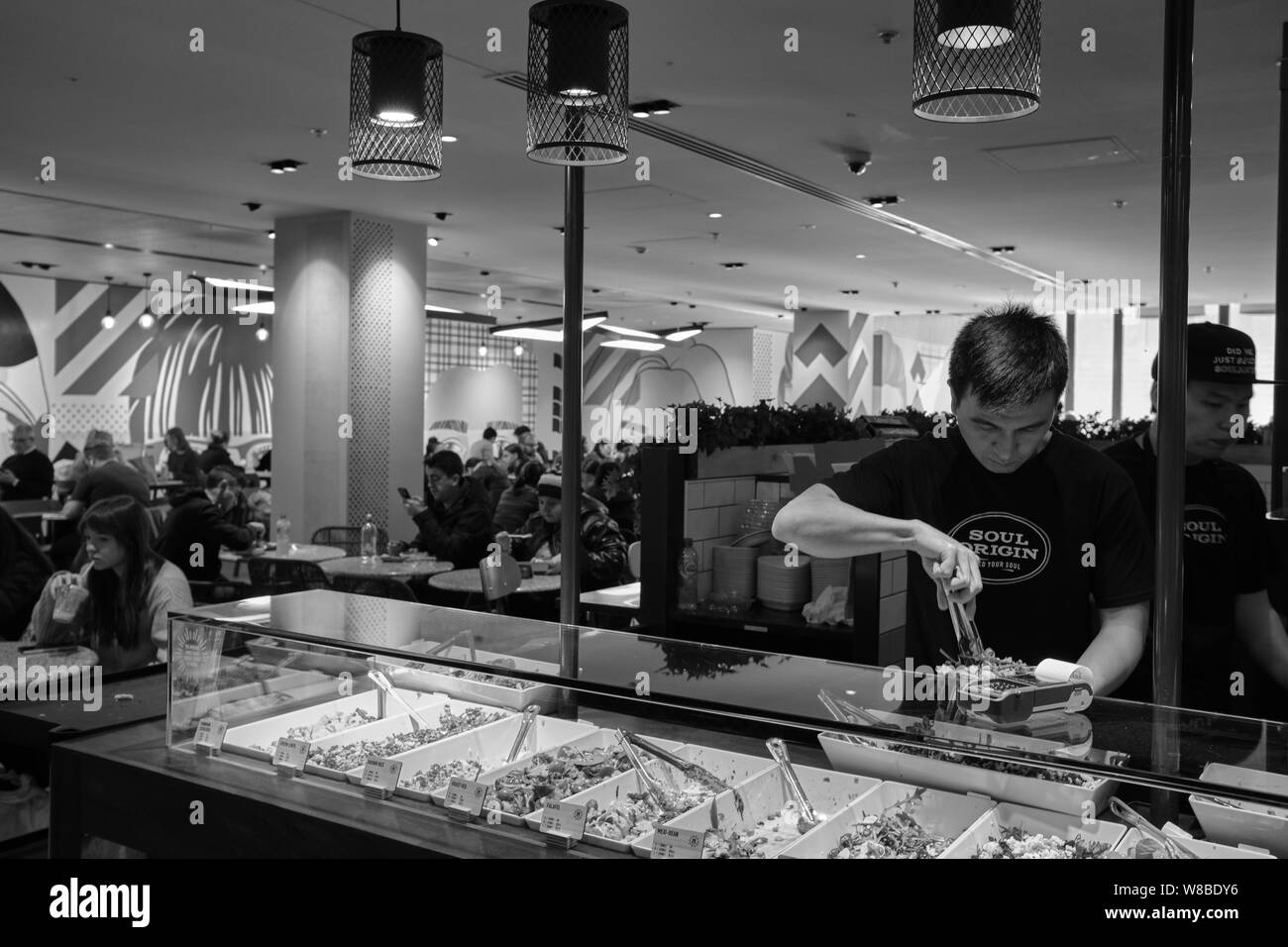 Cafe Arbeiter die Zubereitung von Speisen zur Mittagszeit Kunden in Melbourne Central. Melbourne, Australien. Stockfoto