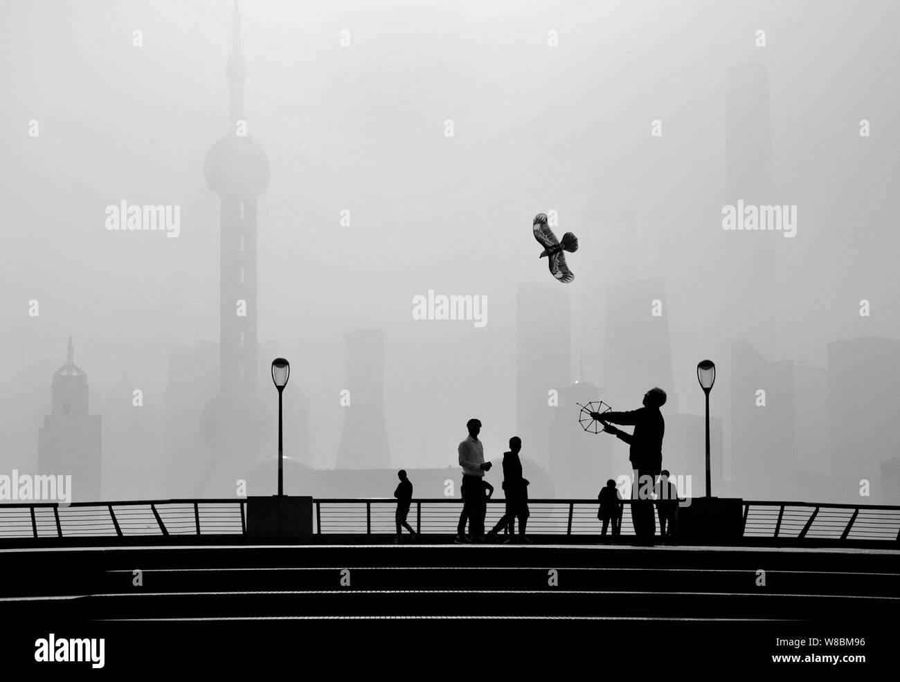 ---- Touristen zu Fuß auf den Bund gegen einen Blick auf die Hochhäuser und Wolkenkratzer in schweren Smog in der Lujiazui Finanzviertel in Pudong, Sh Stockfoto