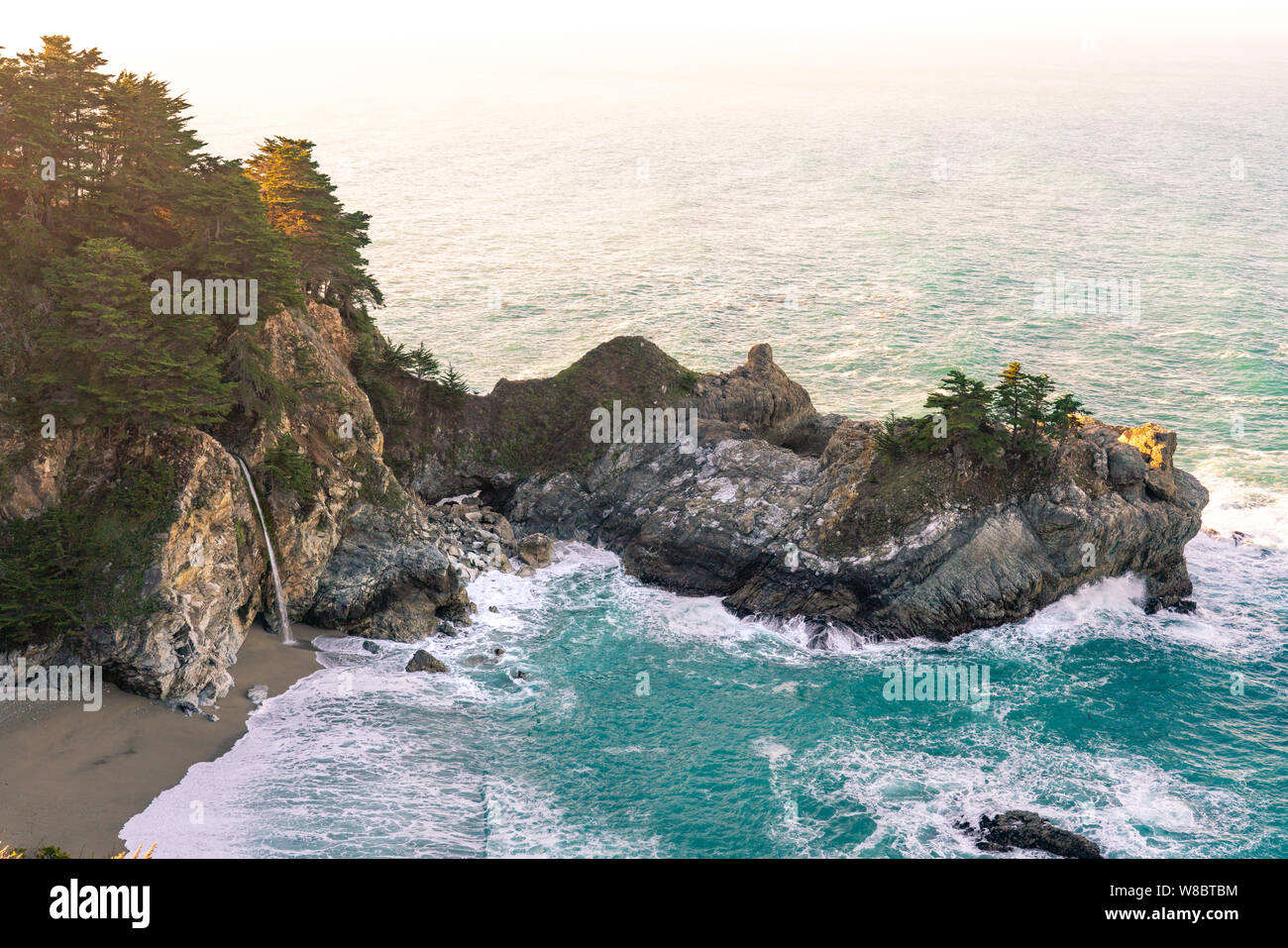 Warmes Morgenlicht, das über den McWay Falls entlang der Küste von Big Sur in Kalifornien gewaschen wird. Stockfoto