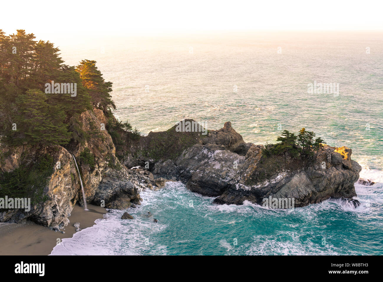 Warmes Morgenlicht, das über den McWay Falls entlang der Küste von Big Sur in Kalifornien gewaschen wird. Stockfoto