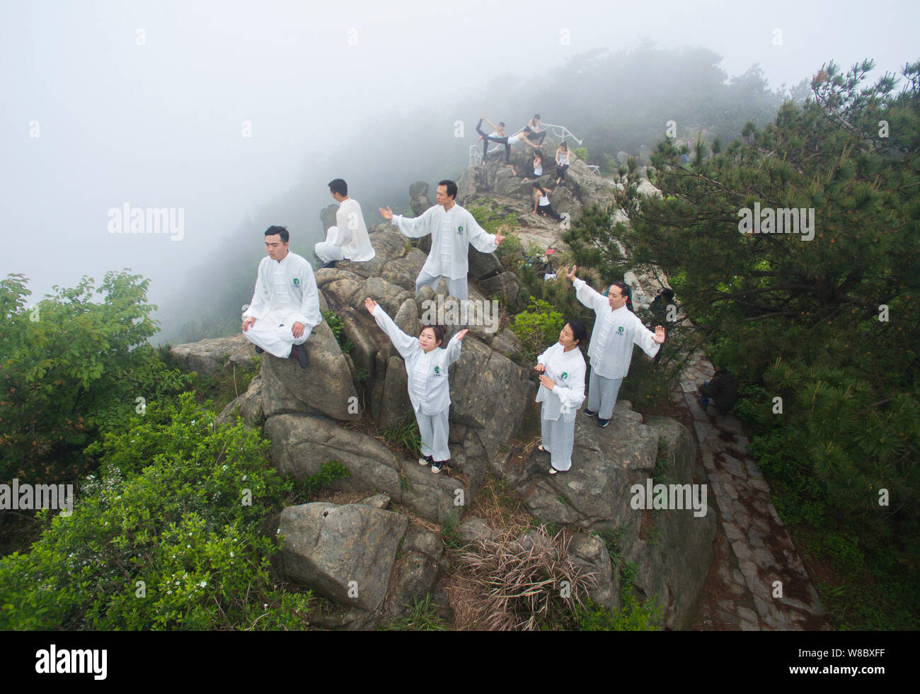 Die chinesischen Menschen führen Tai Chi und Yoga auf dem Gipfel des Shuangfeng Berg in Xiaogan Stadt, der Provinz Hubei in Zentralchina, 24. April 2016. Yoga fa Stockfoto