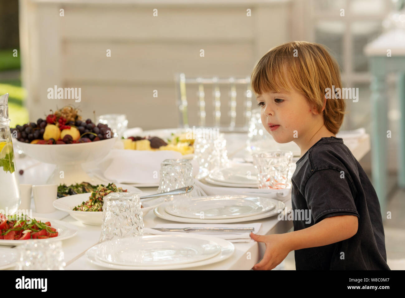 Niedliches Kleinkind am Tisch sitzen für Feier serviert. Stockfoto