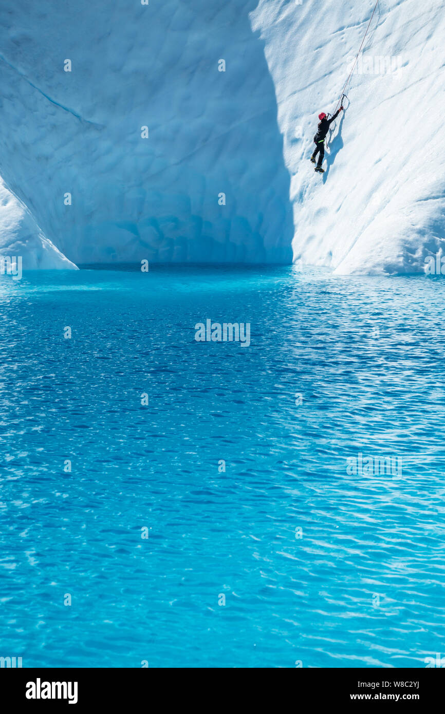 Frau Eis über dem tiefblauen Wasser von einem Gletscher See auf der Matanuska Gletscher in Alaska klettern. Stockfoto
