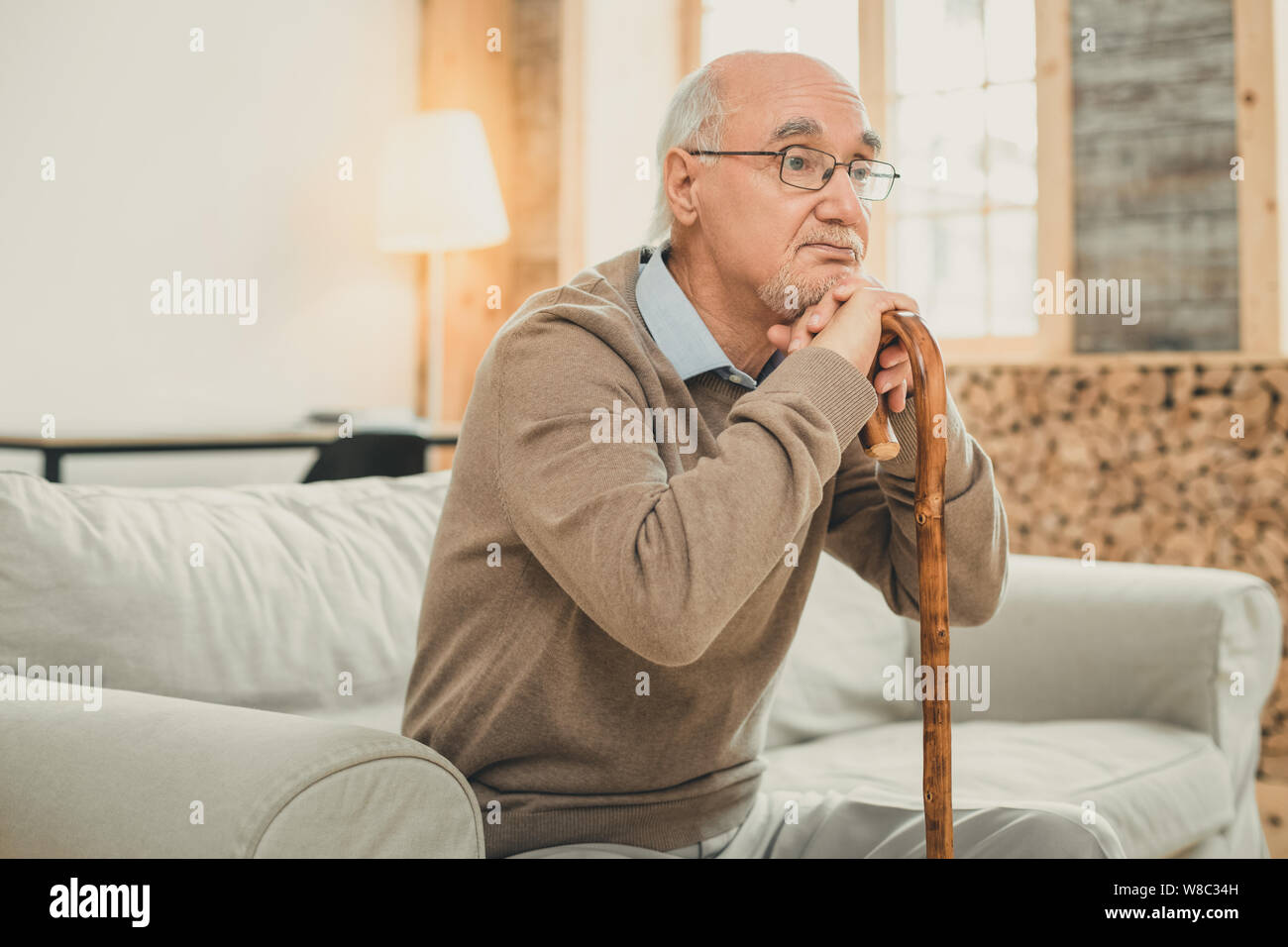 Müde alte Mann mit dem grauen Haar lehnte sich auf dem hölzernen Stock Stockfoto