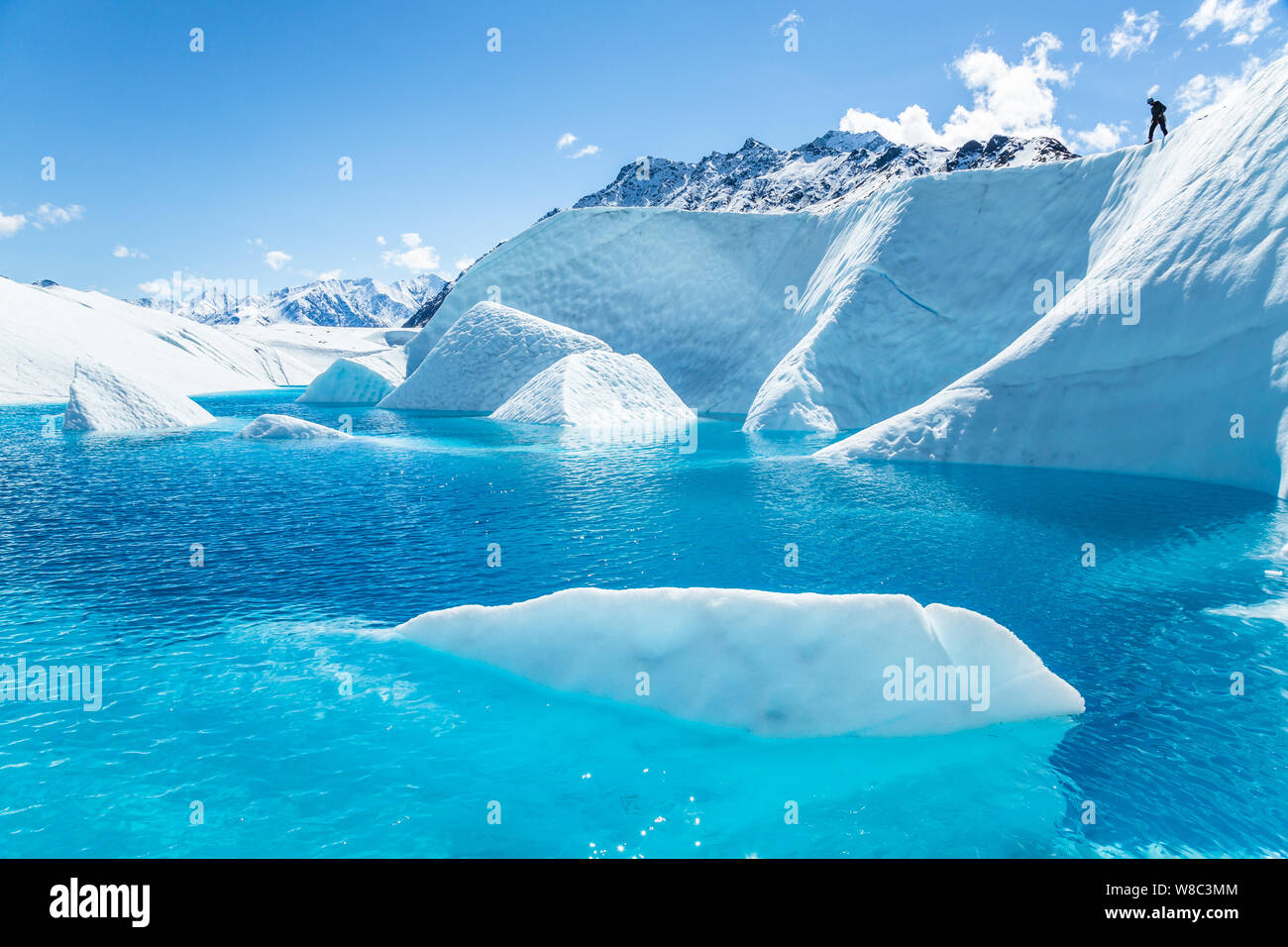 White Ice suchen Wie grosse Eisberge ragt aus einem tiefblauen See auf der Matanuska Gletscher. Ein ice climbing guide Scopes eine Linie ein c zu senken Stockfoto